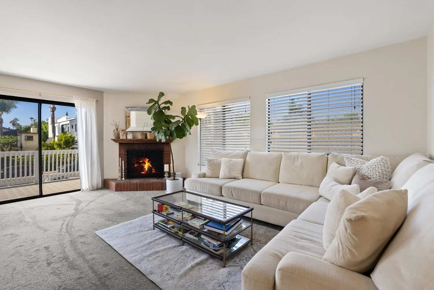 Front home living room with fireplace, sectional sofa and sliding door to the balcony