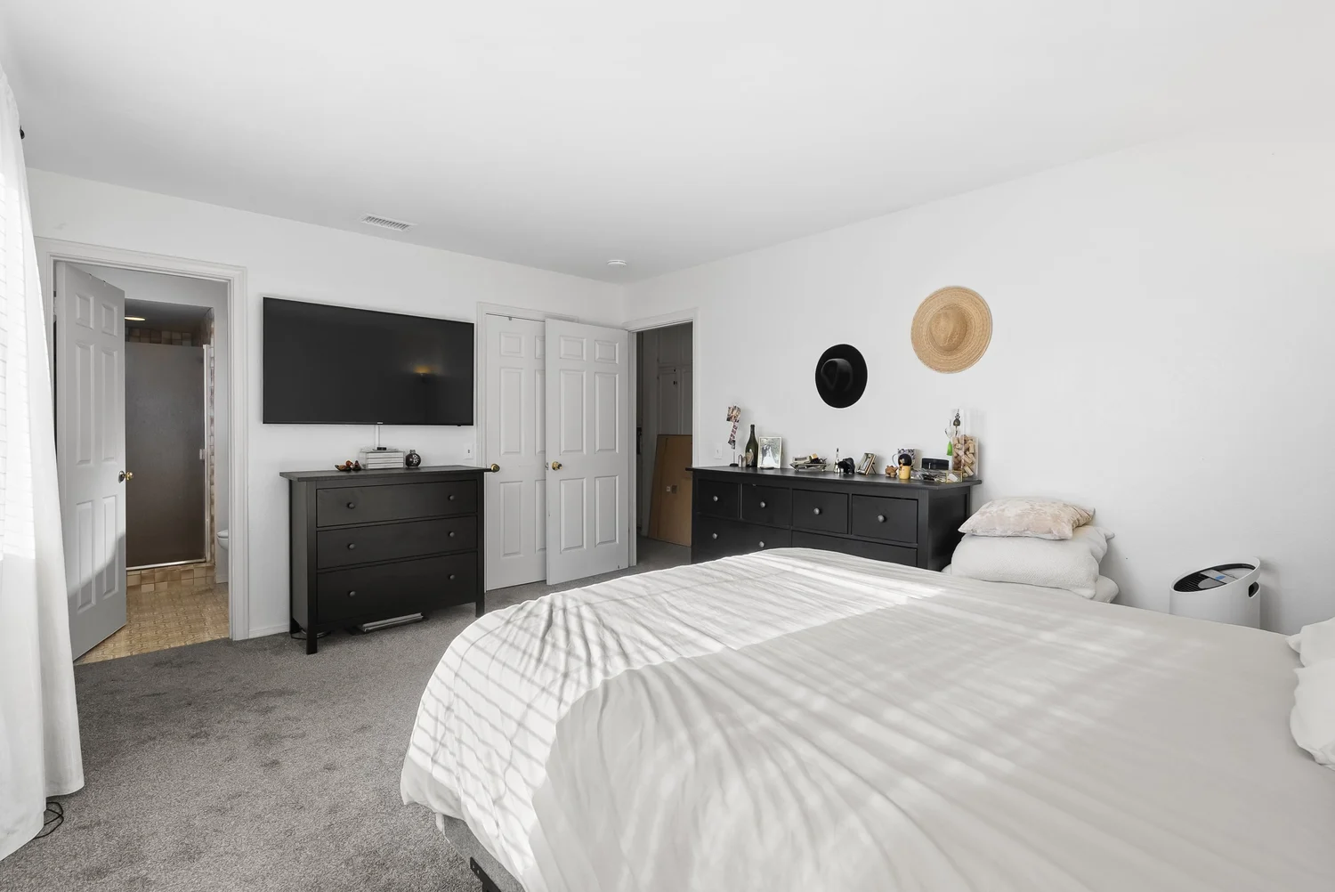 Primary bedroom with dresser and wall-mounted TV