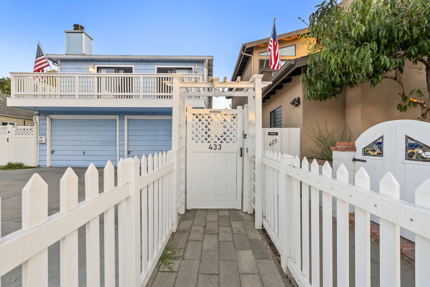 Side gate and paver walkway between white fences
