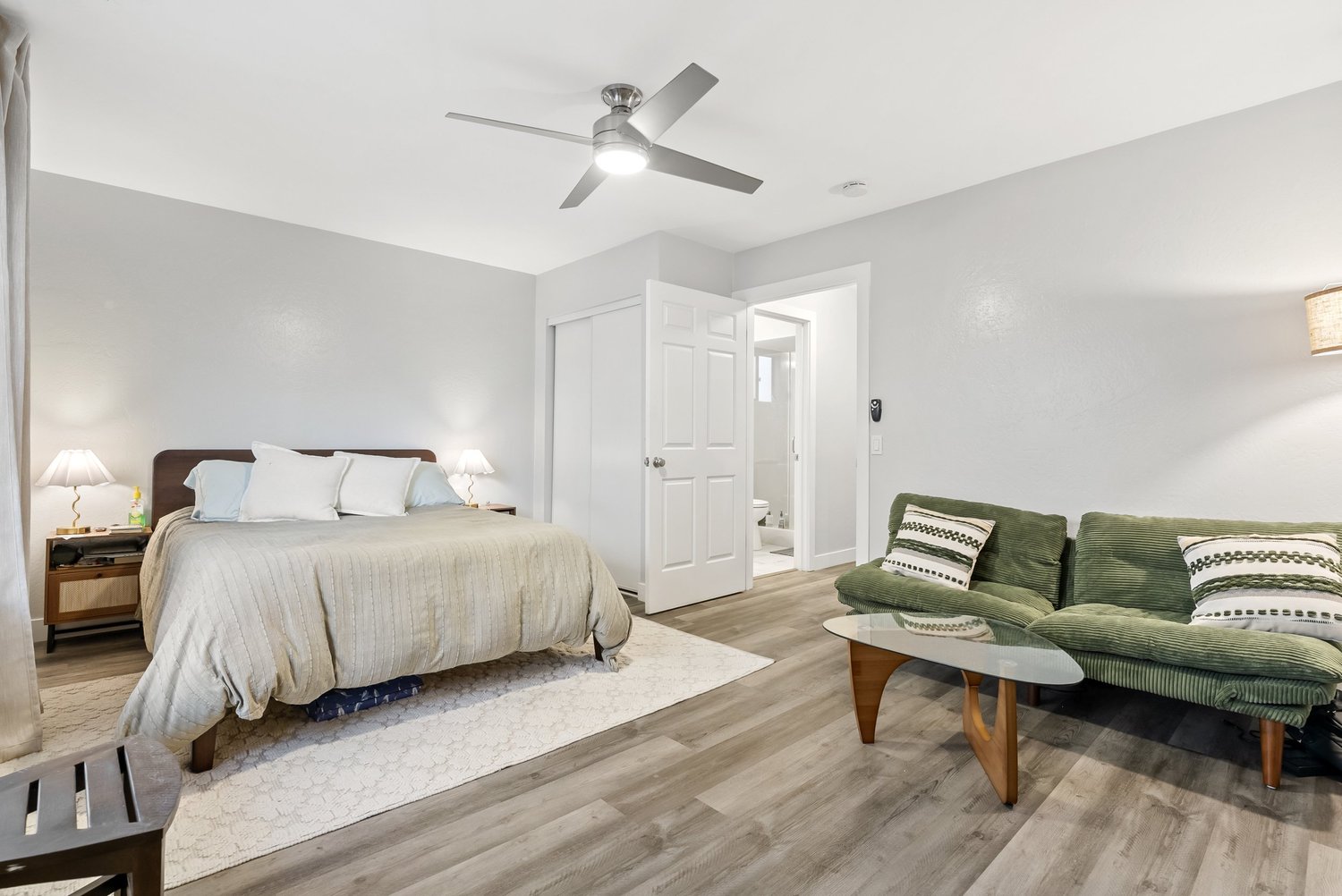 Bedroom with bed, green sofa and ceiling fan