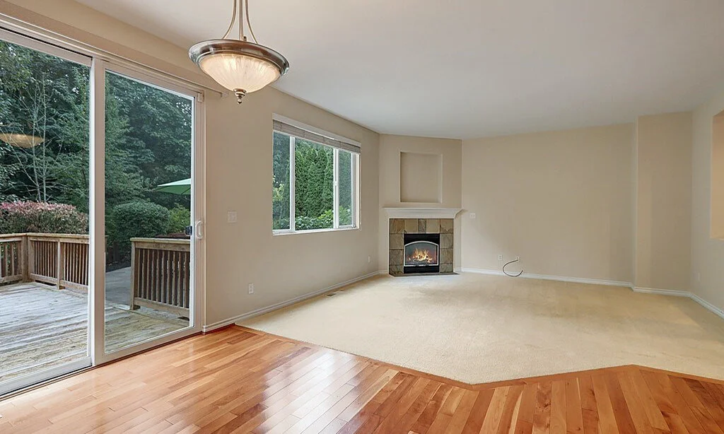 interior of second living room area with carpet and hardwood floors, sliding glass door to patio, window and fireplace