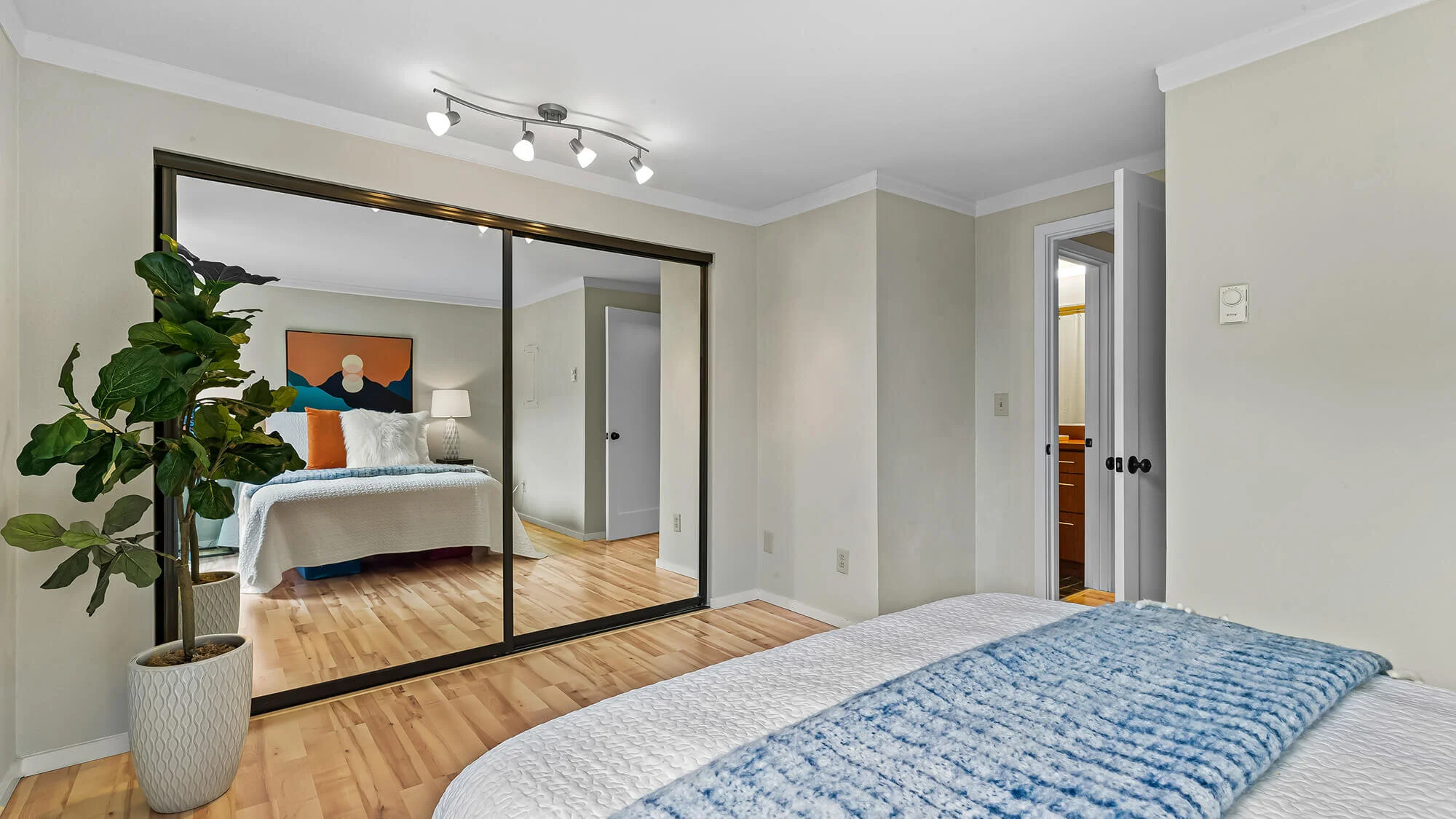 interior of bedroom with hardwood floors, sliding glass door,  mirrored closet, and queen bed