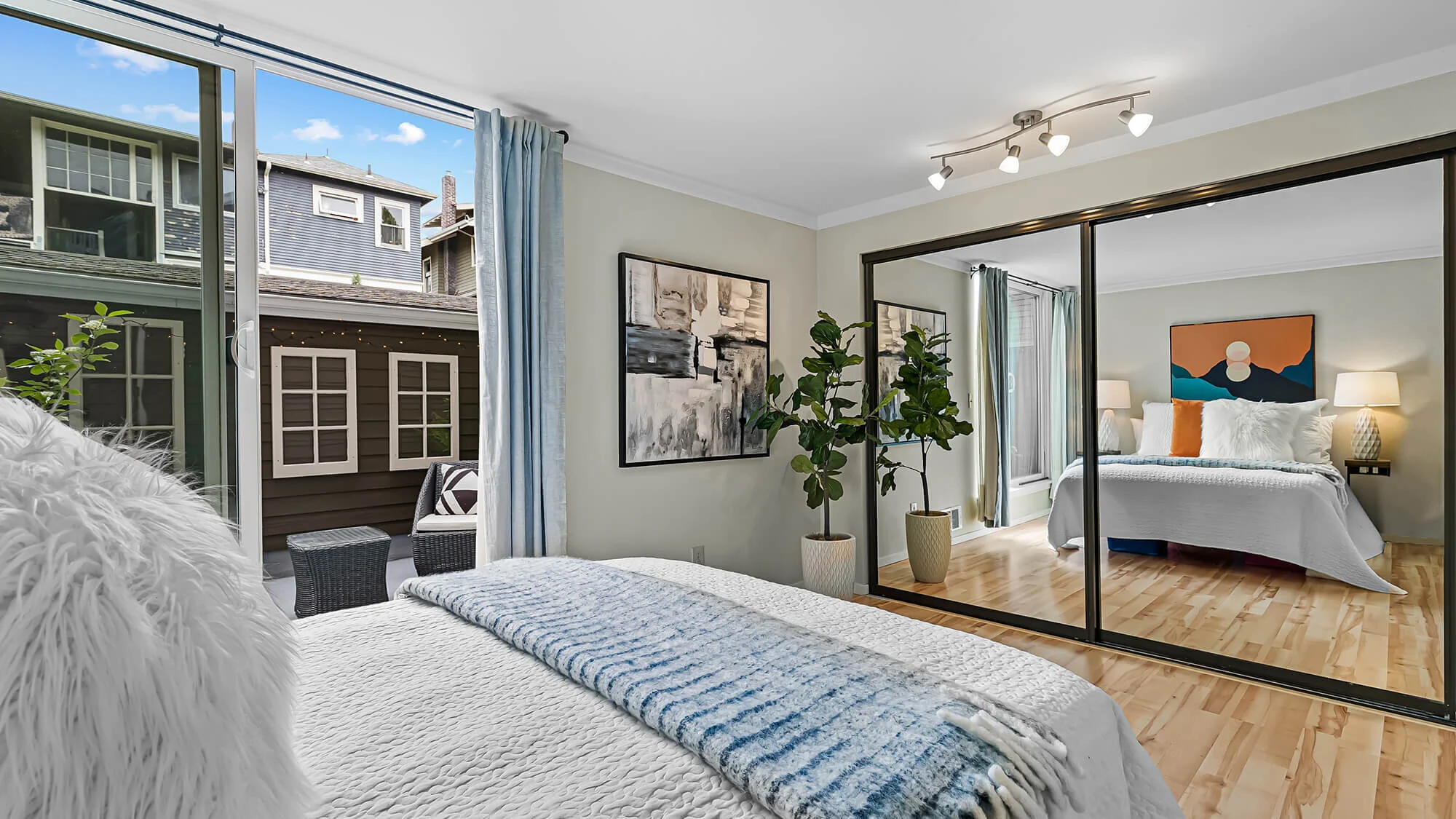 interior of bedroom with hardwood floors, sliding glass door,  mirrored closet, and queen bed