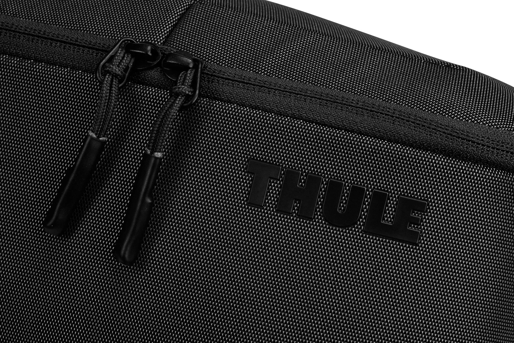 Close-up of the zipper pull and embossed Thule logo on a black toiletry bag