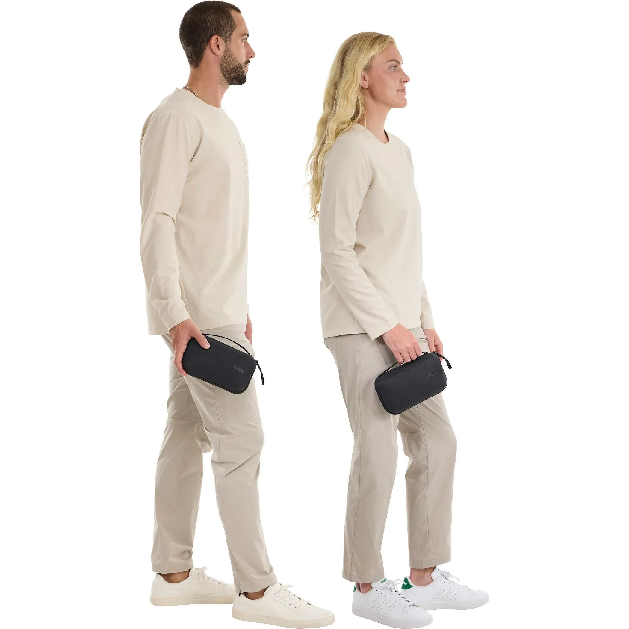Two travelers standing and holding black Thule Aion travel organizers at their sides