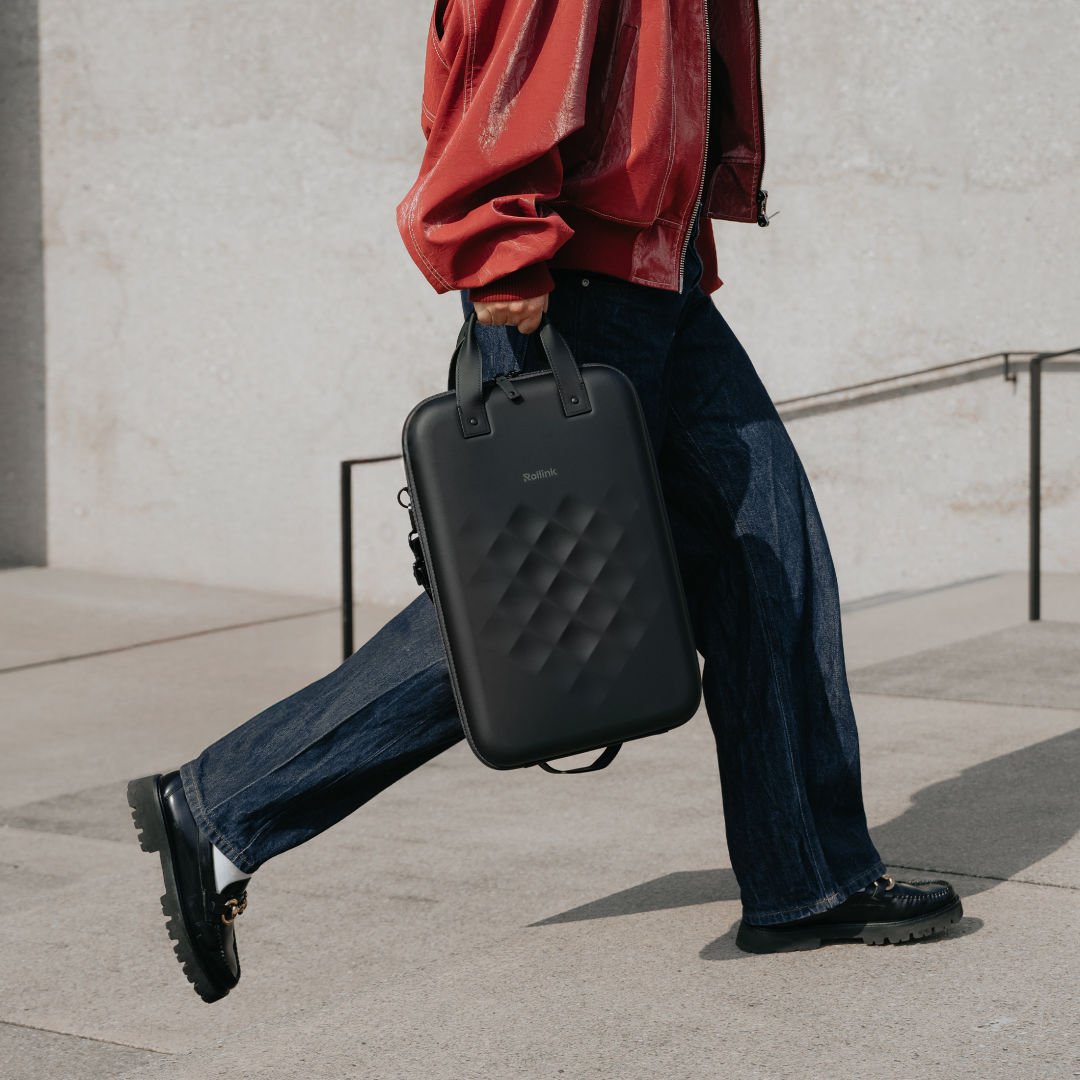 Person walking outdoors carrying a Rollink Go vertical laptop case by its handles