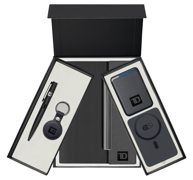 A black gift box with its lid open, containing various tech accessories and accessories packaging with the TD logo. Inside, there is a pen, a keychain, a portable charger, and a wireless charging pad.