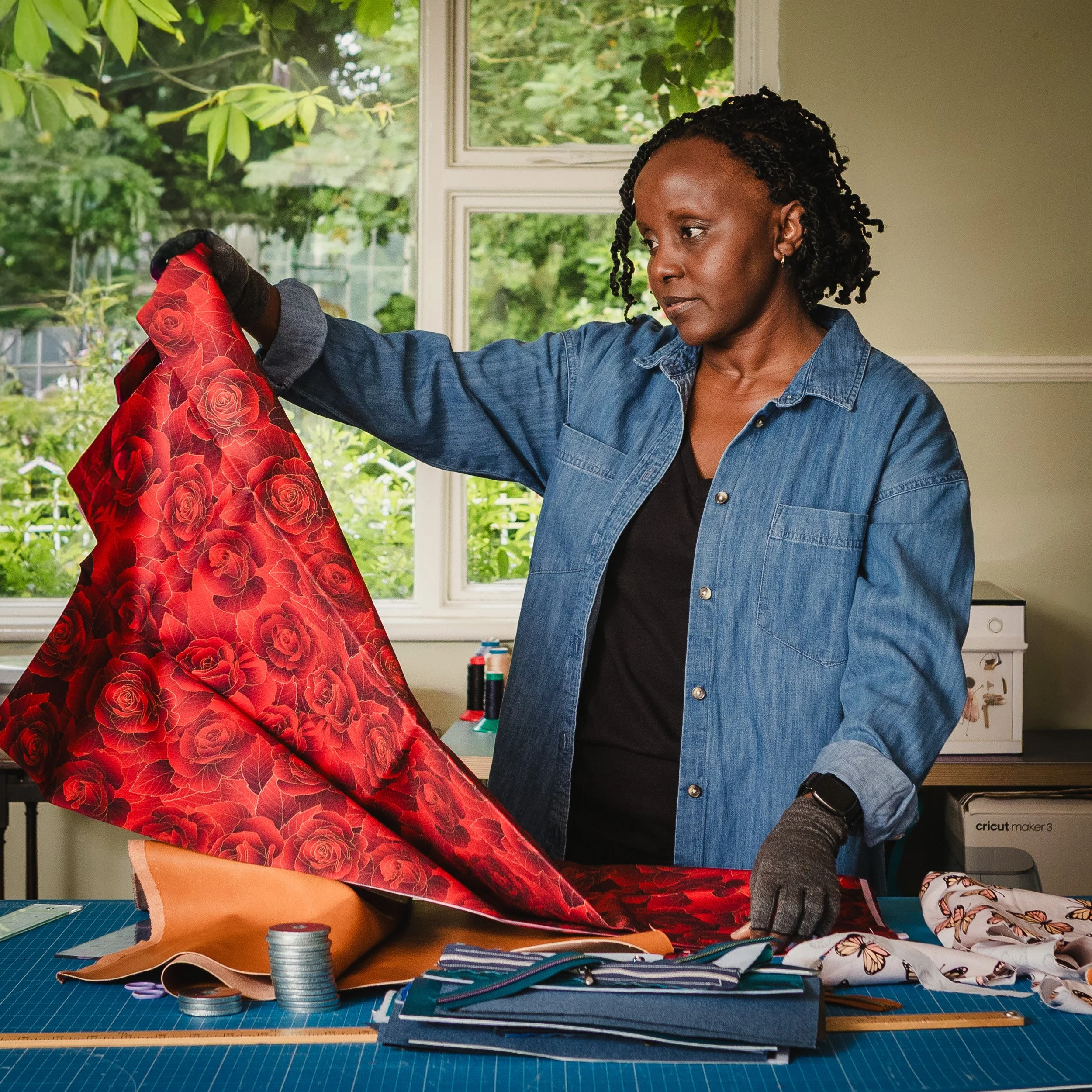 Textile designer holding red rose fabric in her sewing studio