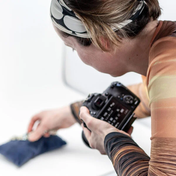 Woman looking through her camera while photographing a product during a practical workshop.