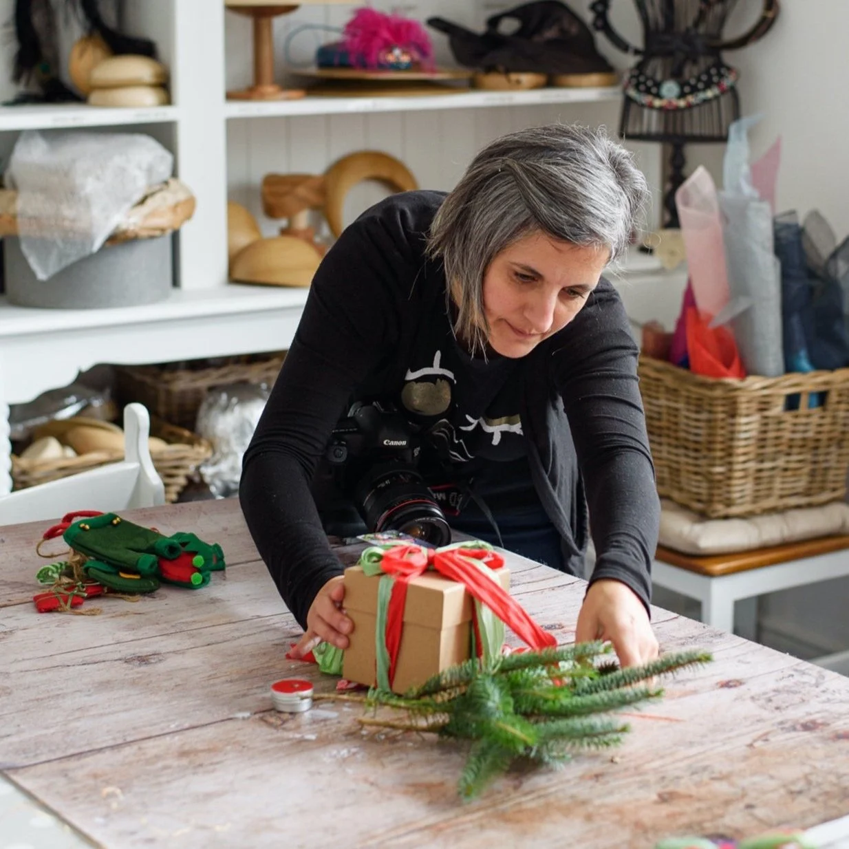 Ana Dorado arranging greenery around a wrapped gift on a worktable.