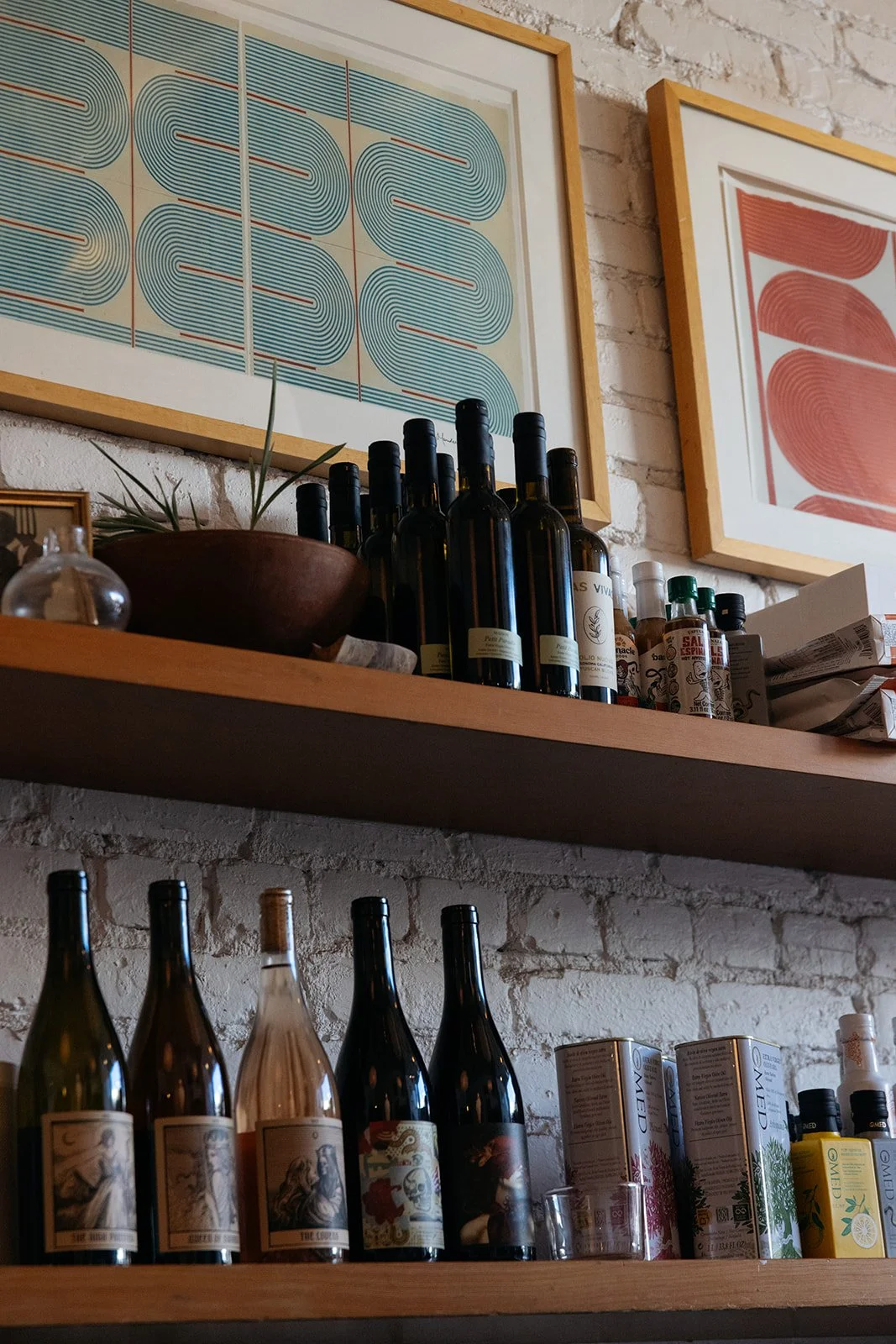 Wine bottles, olive oil and plants on shelves inside Crudo e Nudo