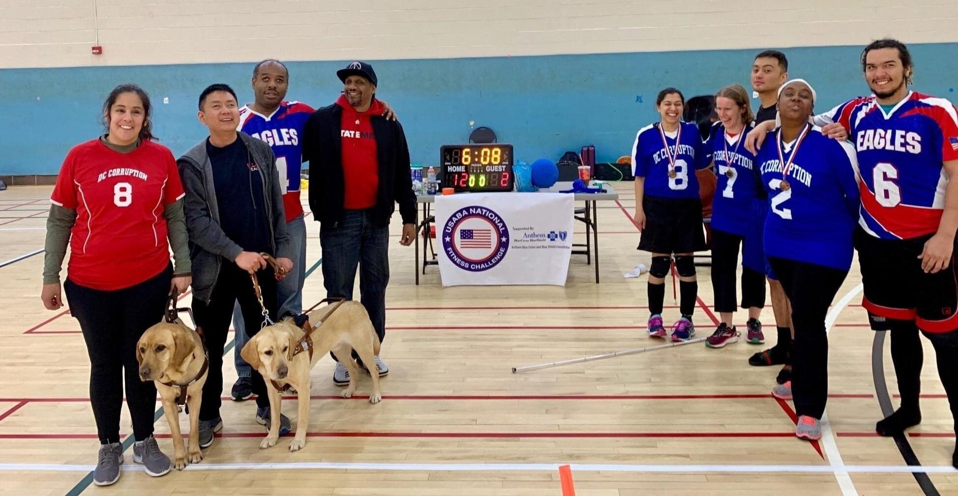 Photo taken after WMABA tournament, spring 2019. Several players in the photo, most wearing team jerseys. Some have medals on their chests. Behind them is the USABA National Fitness Challenge banner.
