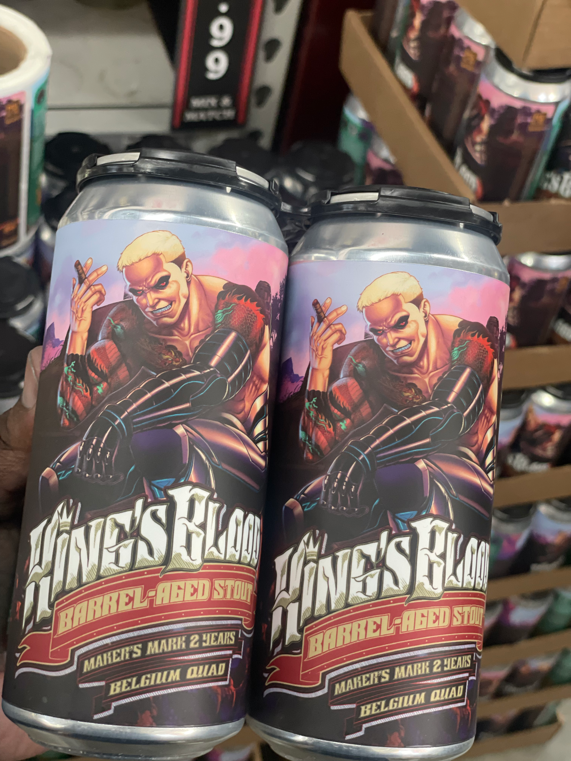 Cans with a colorful, illustrated graphic featuring a smiling, punk-style person with spiky hair, wearing black gloves and a jacket, holding a cigar in one hand, and a title that reads "Makers Mark Single Barrel  2 Years".