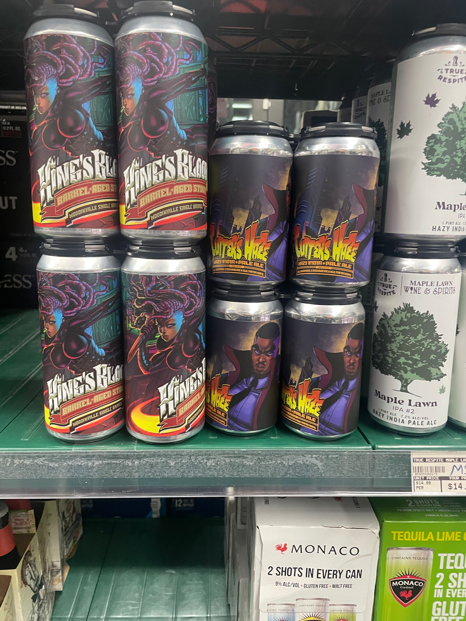 Stacks of beer cans on store shelf, featuring colorful fantasy artwork and graphic labels. The cans in the foreground have a fantasy theme with a dragon and a woman, while the cans in the background are labeled Maple Dawn, with images of trees.