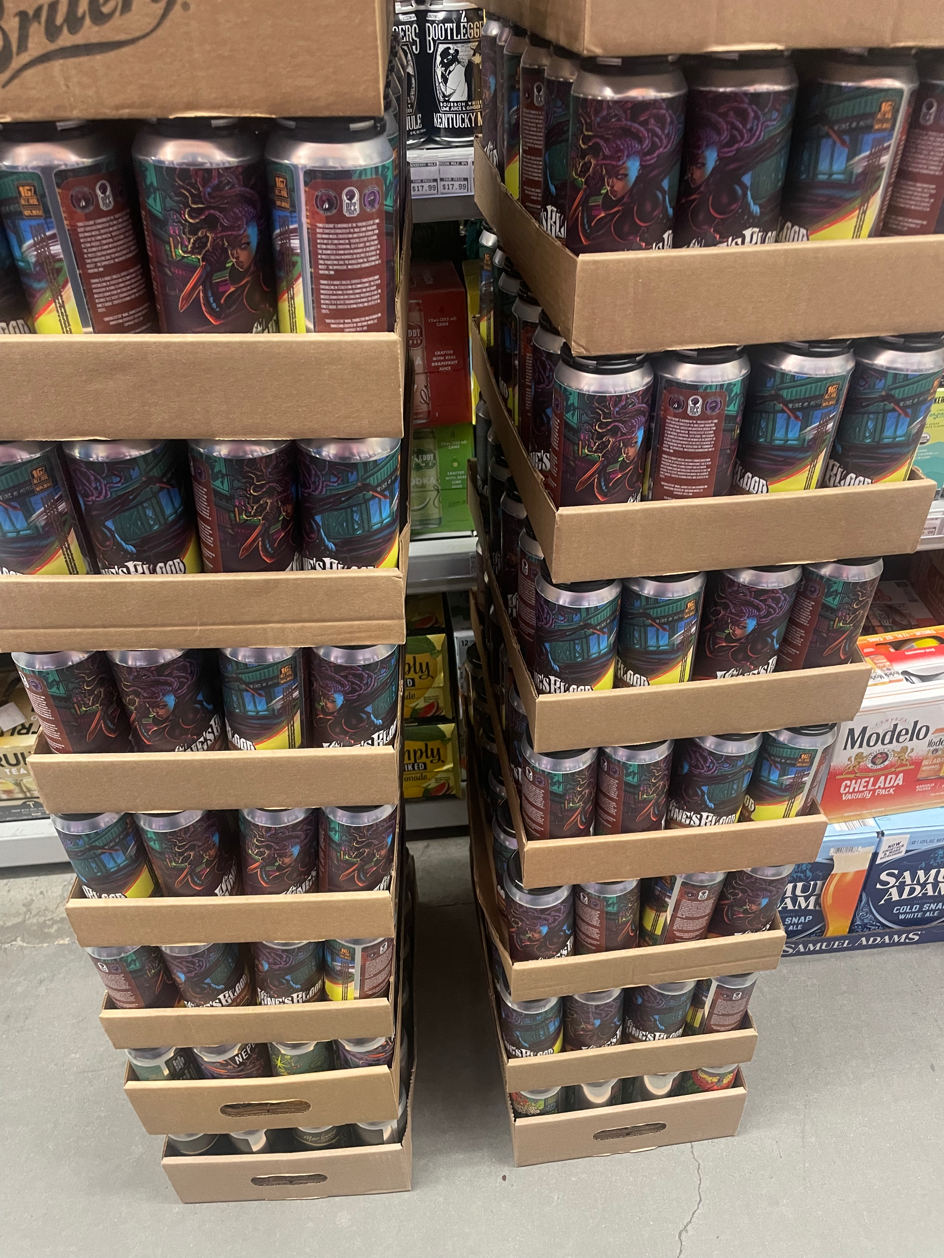Stacks of canned beverages arranged on cardboard racks in a store aisle.