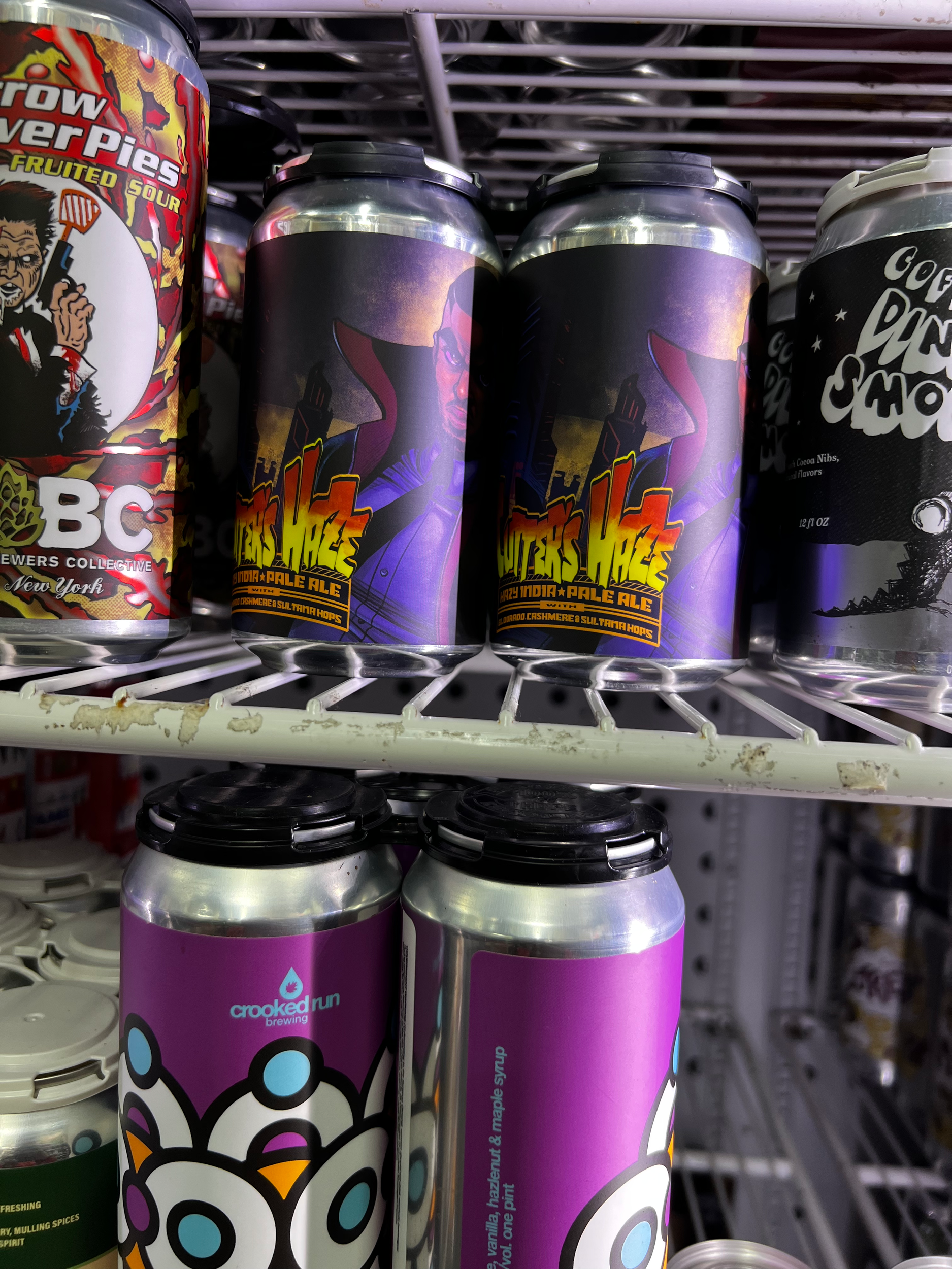 Cans of craft beer on a store shelf, featuring colorful and graphic labels.