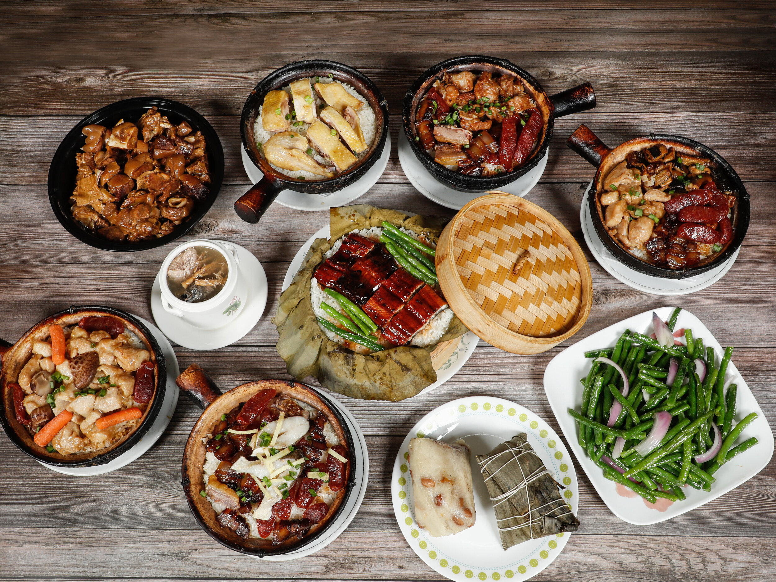 Clay pots, lotus leaf rice, soup and vegetables on a table at Clay Pot House