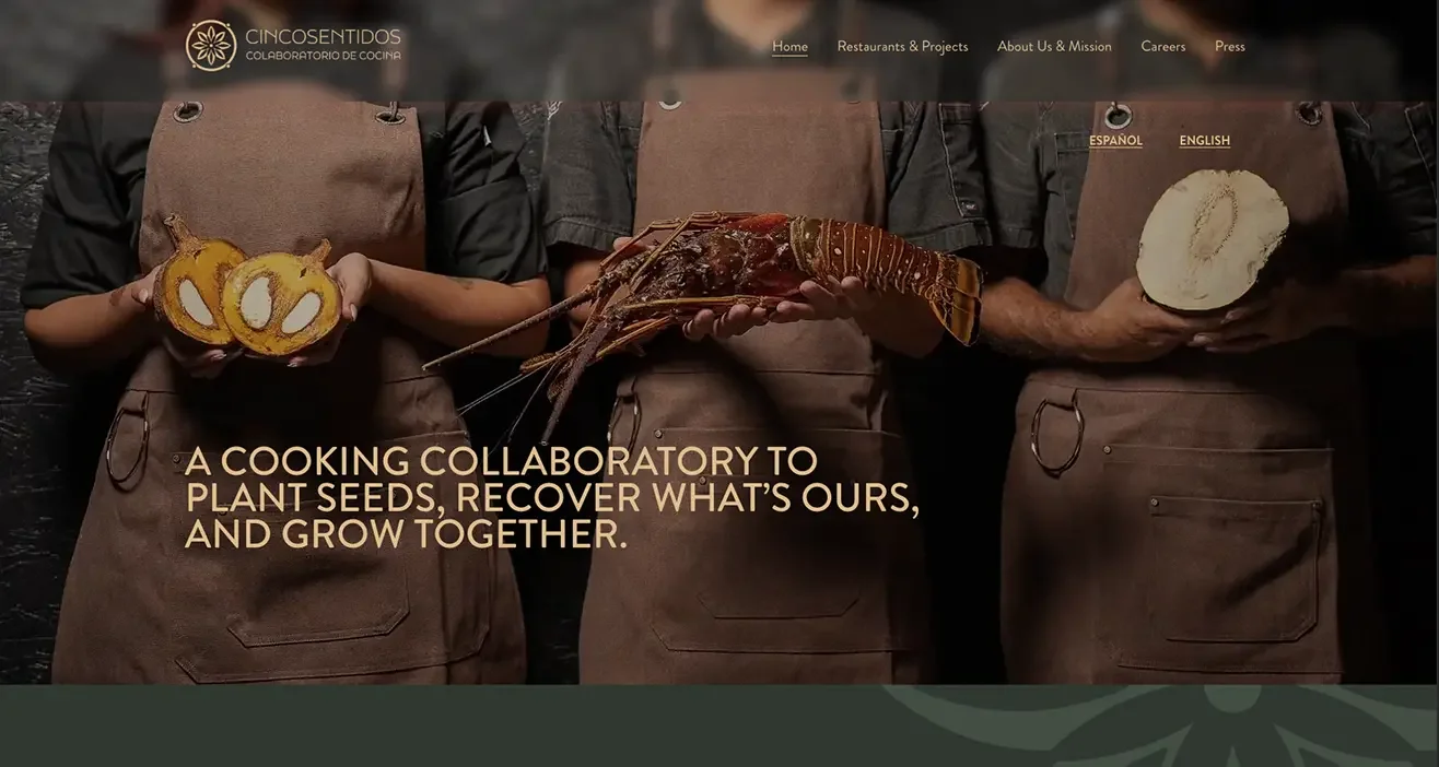 Chefs wearing brown aprons holding fresh local ingredients, cacao, and lobster for Cincosentidos web hero banner