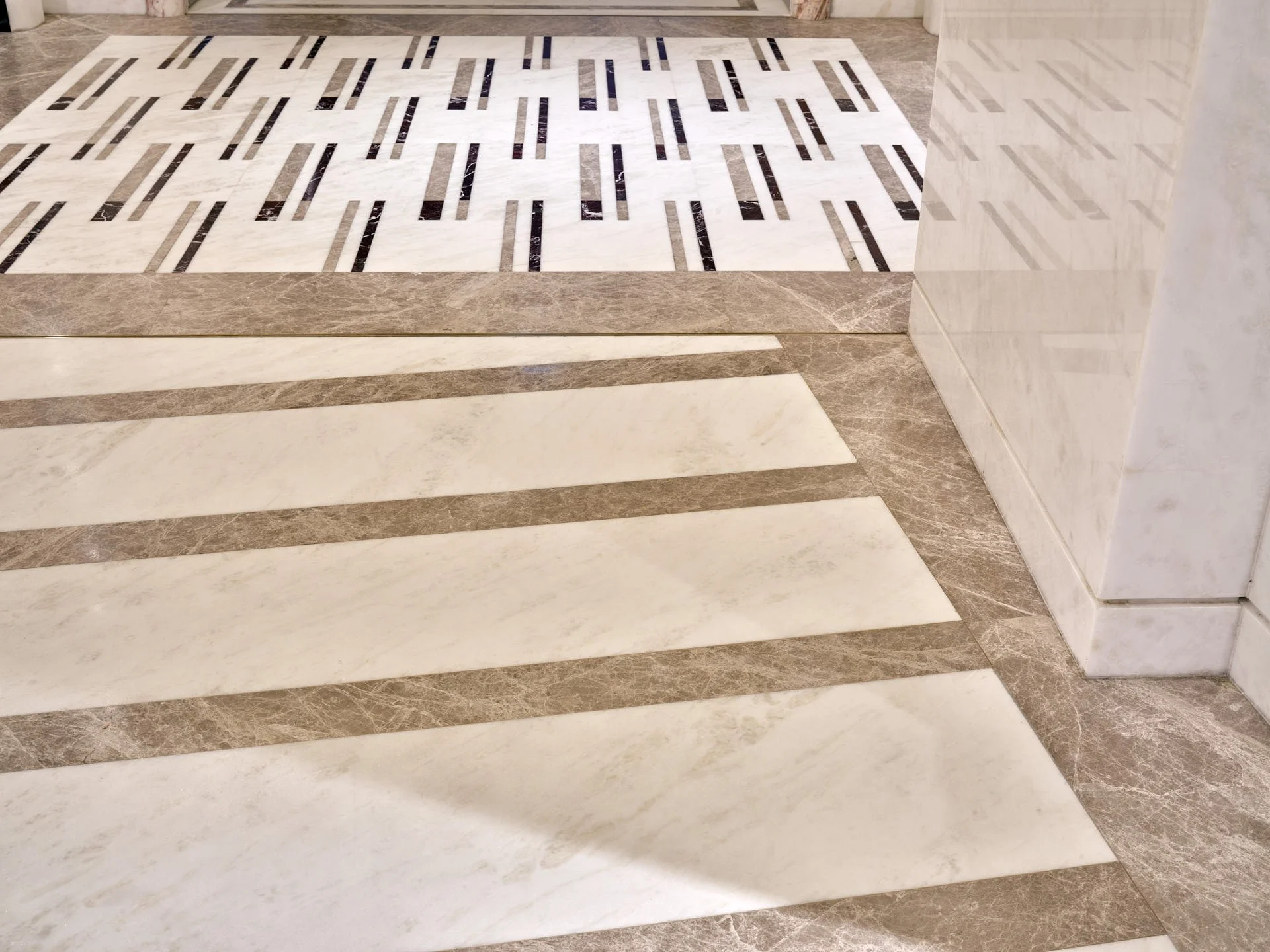 Close view of striped and finely inlaid marble floor patterns beside a polished white wall cladding by stoneCIRCLE - photo Marco Joe Fazio STUDIO