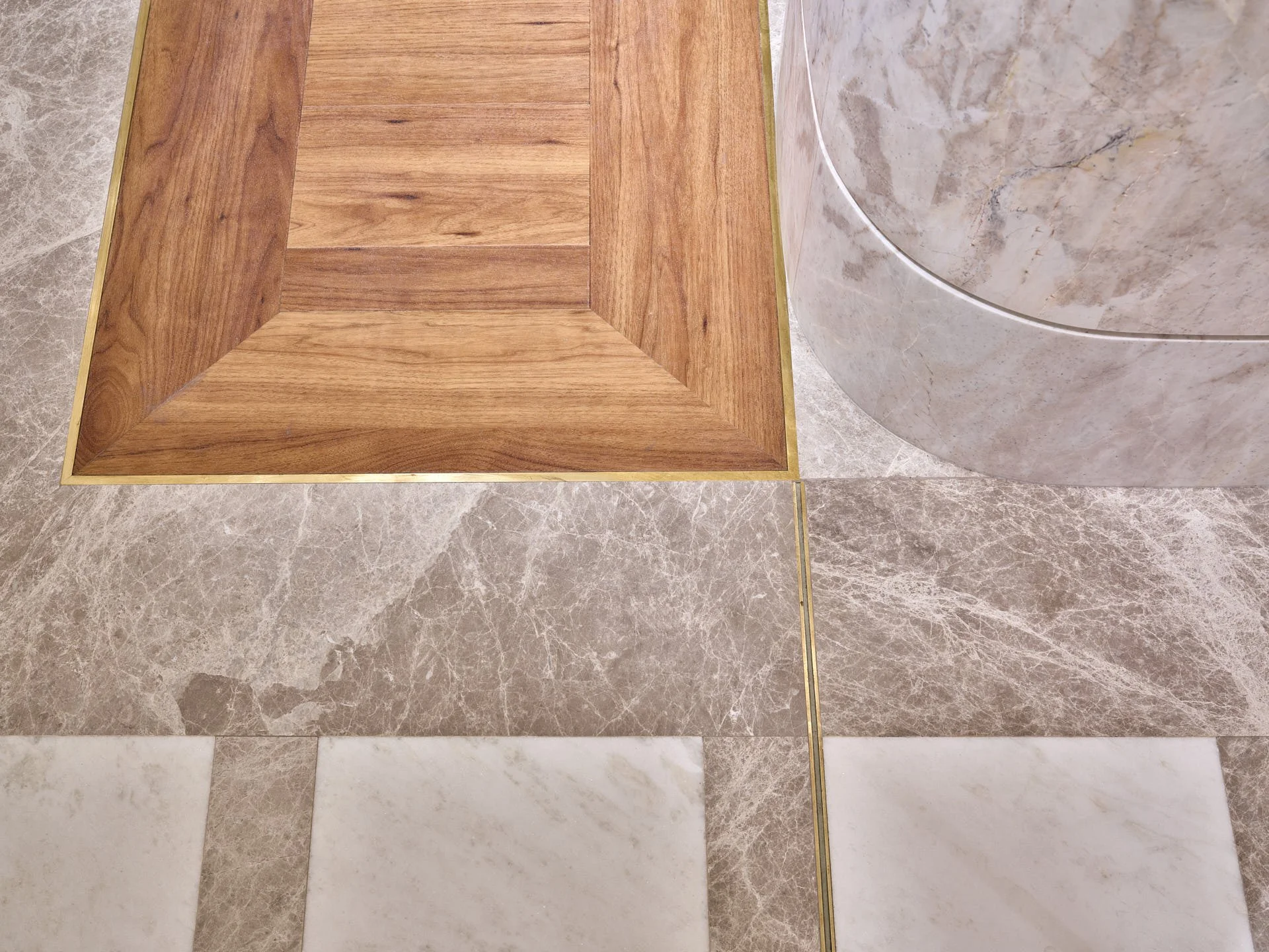 Overhead detail of grey marble flooring, timber display flooring, metal trims and a rounded Calacatta Matarazzo-clad column by stoneCIRCLE - photo Marco Joe Fazio STUDIO