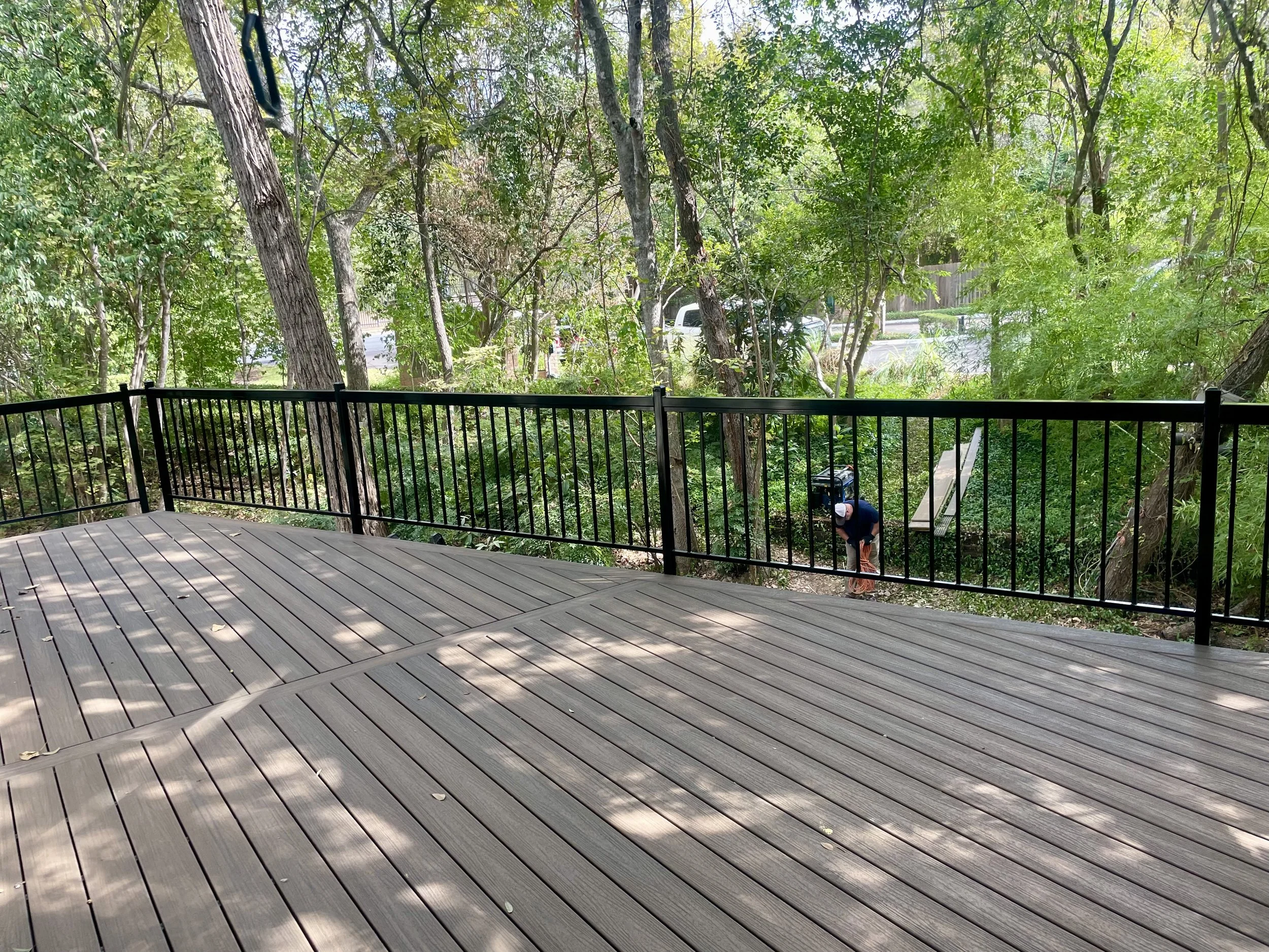 Deck with black vertical metal railing overlooking a wooded yard.
