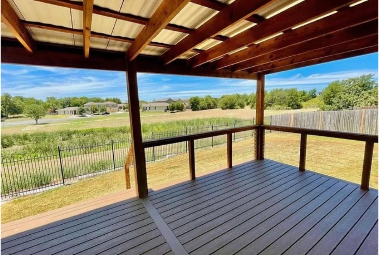 Covered deck with railing overlooking an open landscape.