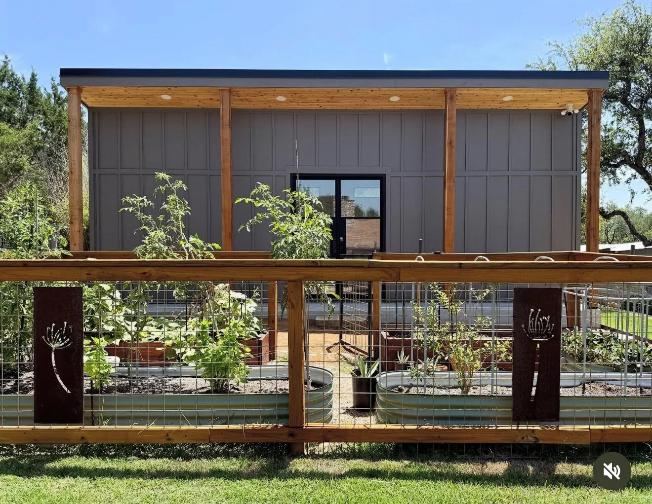 Dark-sided small building with a wood-framed porch and metal railing.
