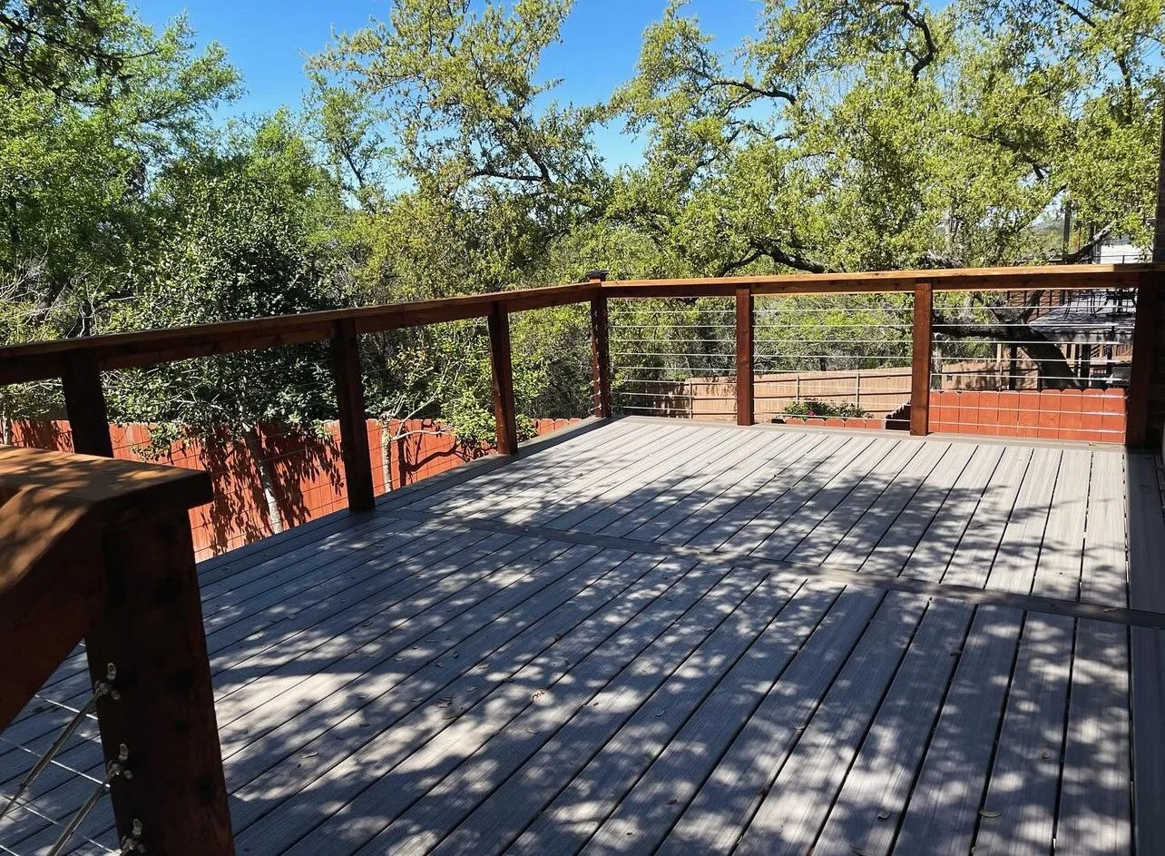 Raised deck with wood and wire railing surrounded by trees.