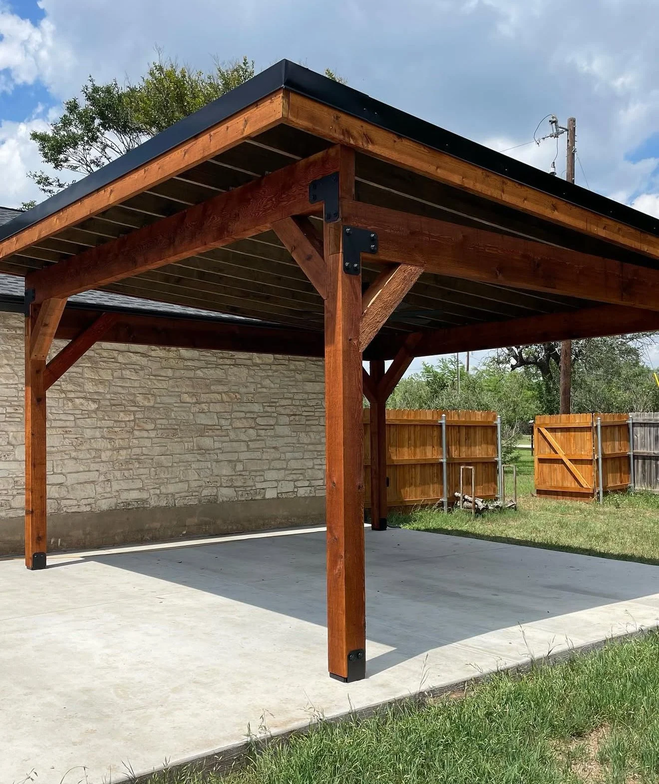 Timber-framed carport with a pitched roof over a concrete pad.