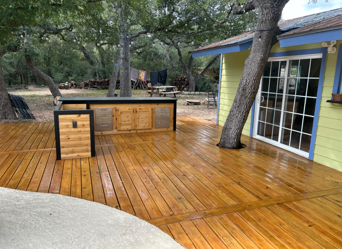 Wood deck built around a tree with an outdoor counter beside a house.