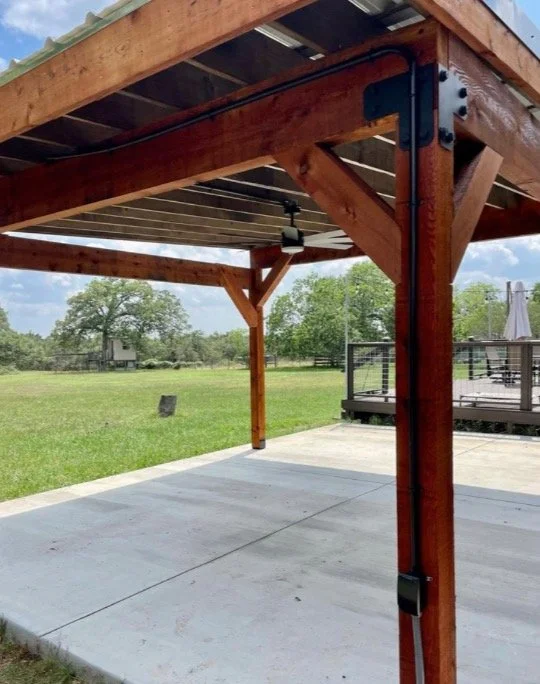 Wood posts and beams supporting a roof over a concrete slab.