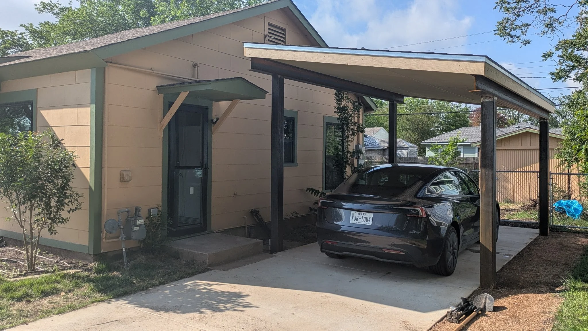Car parked beneath a carport attached to a house.