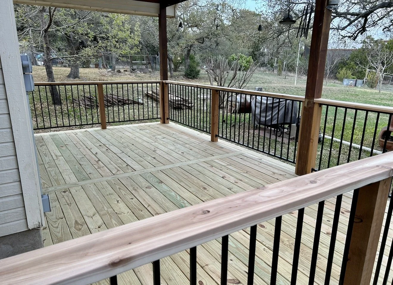 Wood deck with black metal railings overlooking trees.