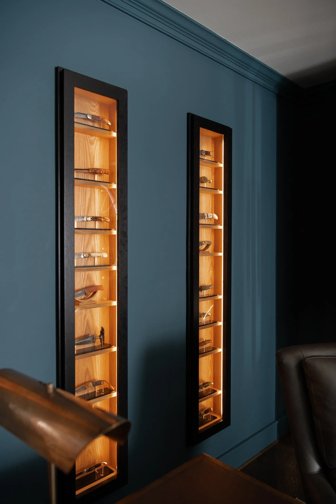 Two tall display cases on a blue wall containing watches.