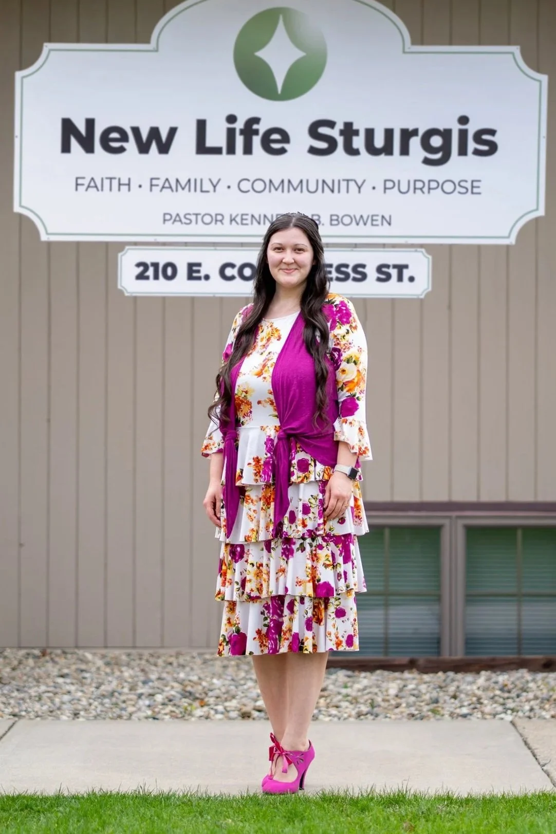 Woman in floral dress standing outside Potter's House Church in Sturgis.
