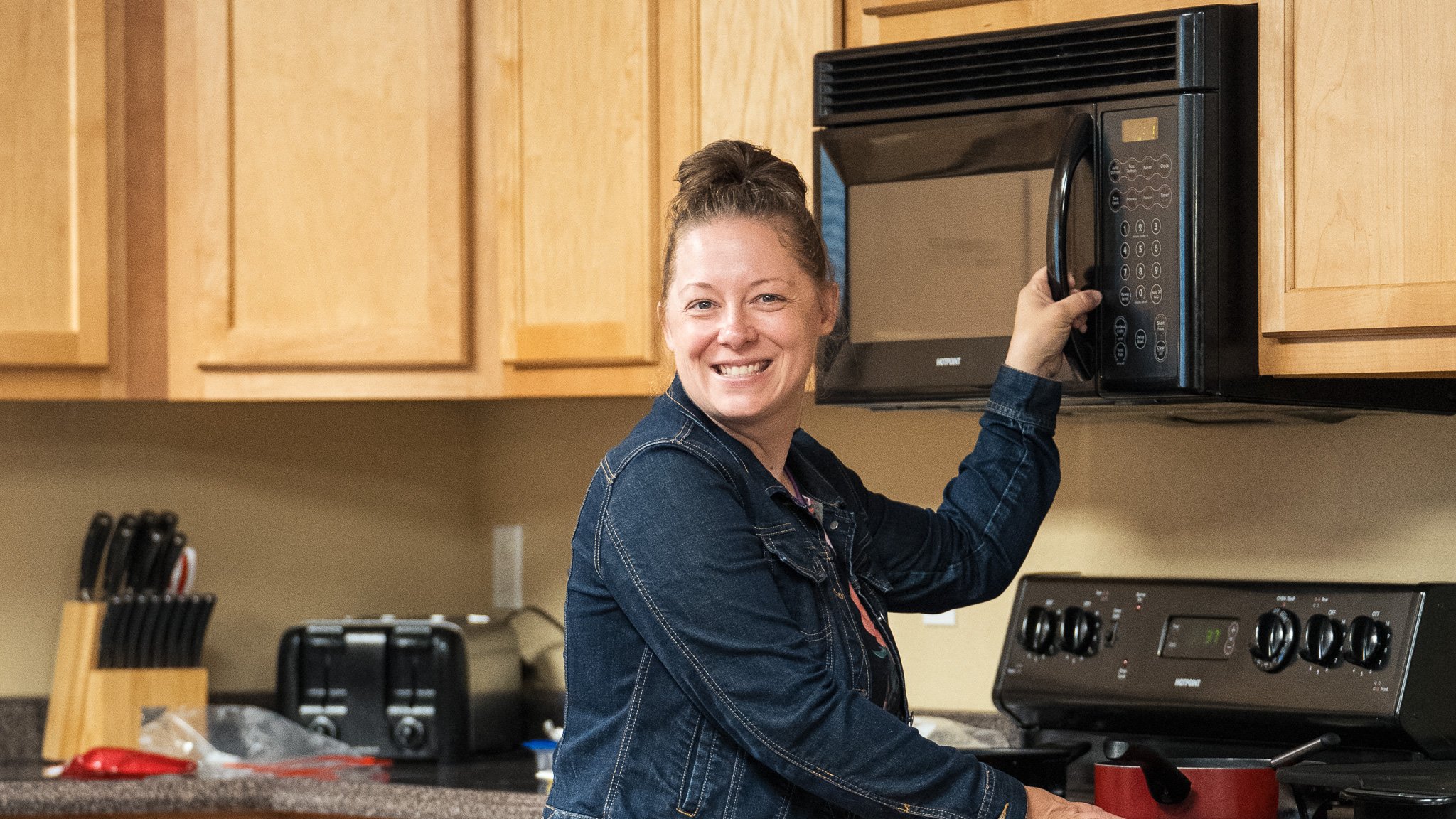 Group of people in a church setting, with two men in suits greeting each other, surrounded by others, including a woman holding a baby.