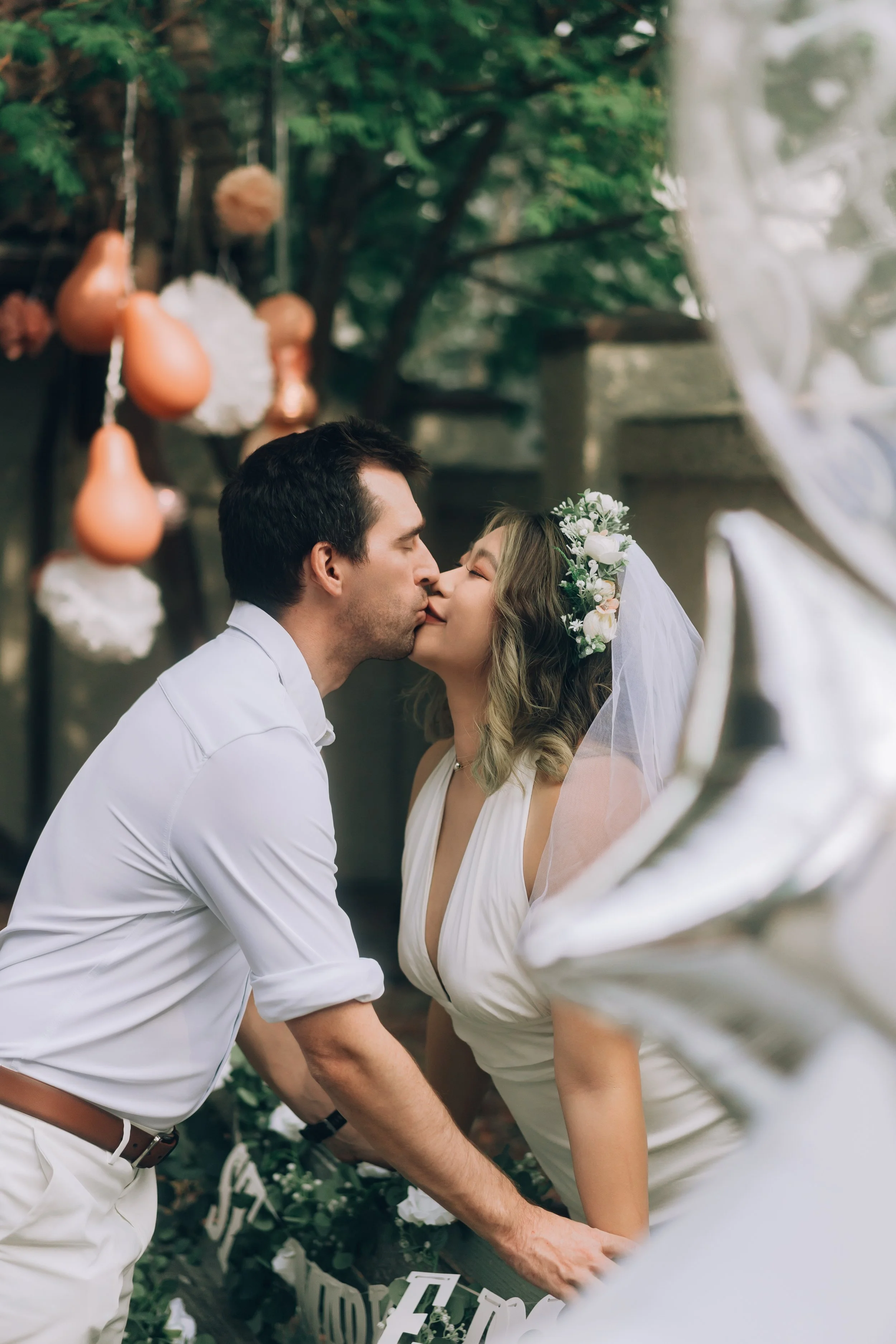 Bride and groom kissing outdoors with floral decorations