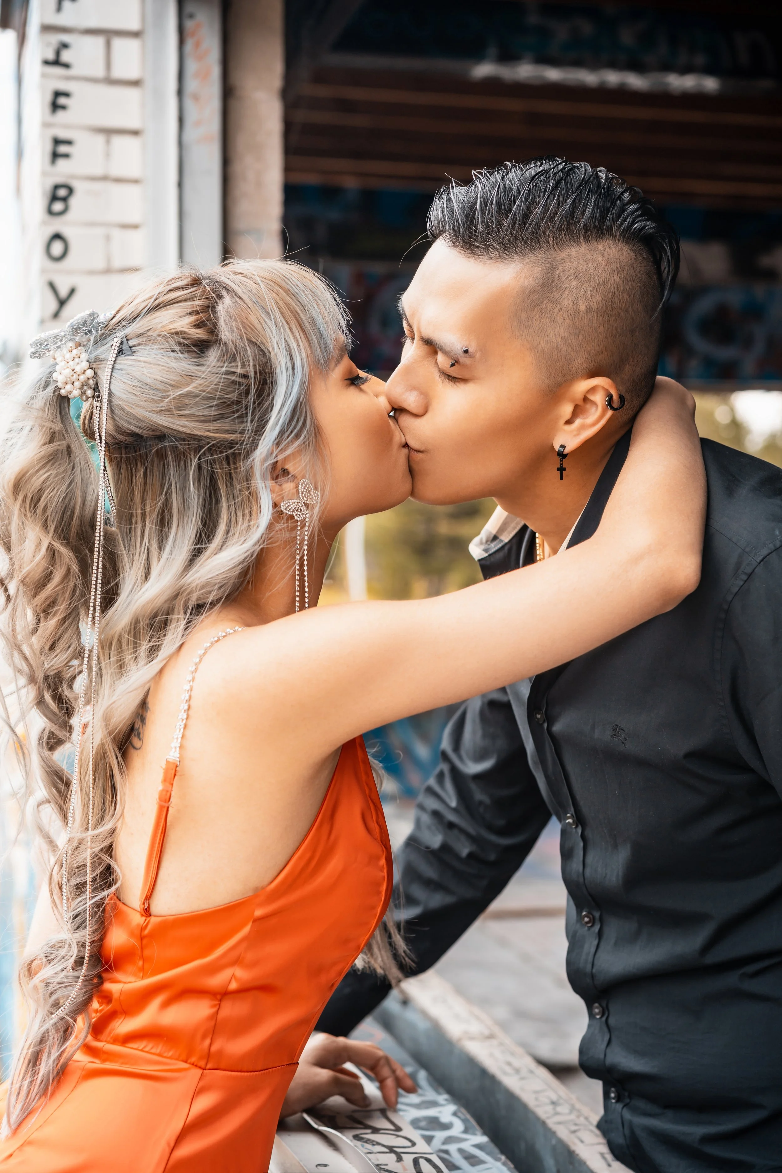 Couple kissing near graffiti wall.