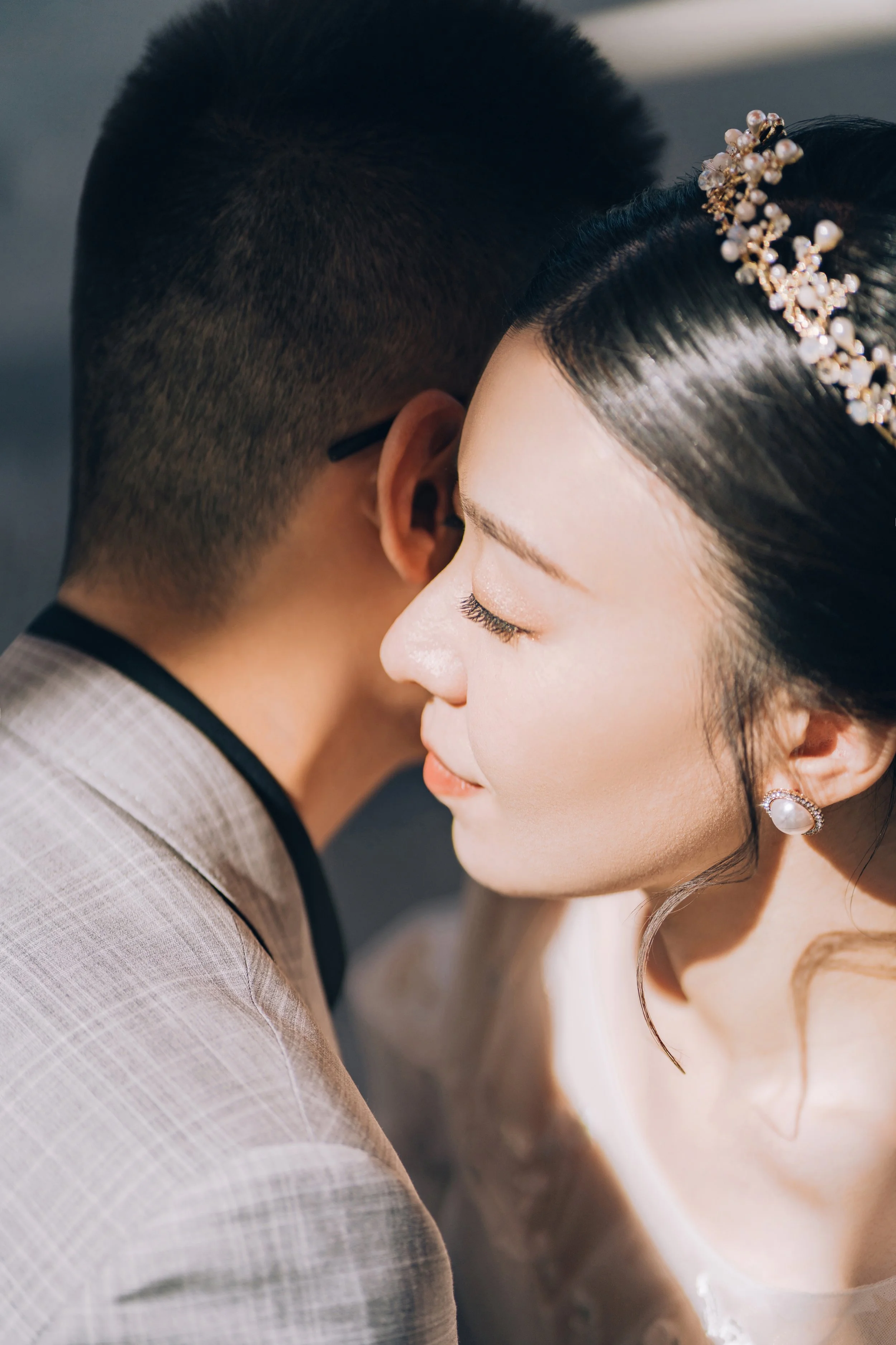Close-up of a bride and groom embracing with their faces close, eyes closed, and serene expressions, capturing an intimate moment during their wedding.
