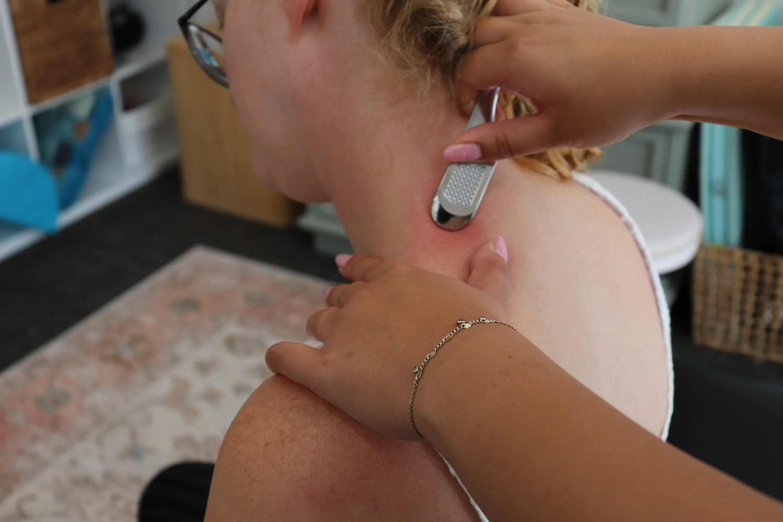 Port Elgin Chiropractors Dr. Tuason and Dr. Burns are pictured. Instrument-assisted soft tissue mobilization using a small metal tool is the technique pictured being used on the patient's neck.