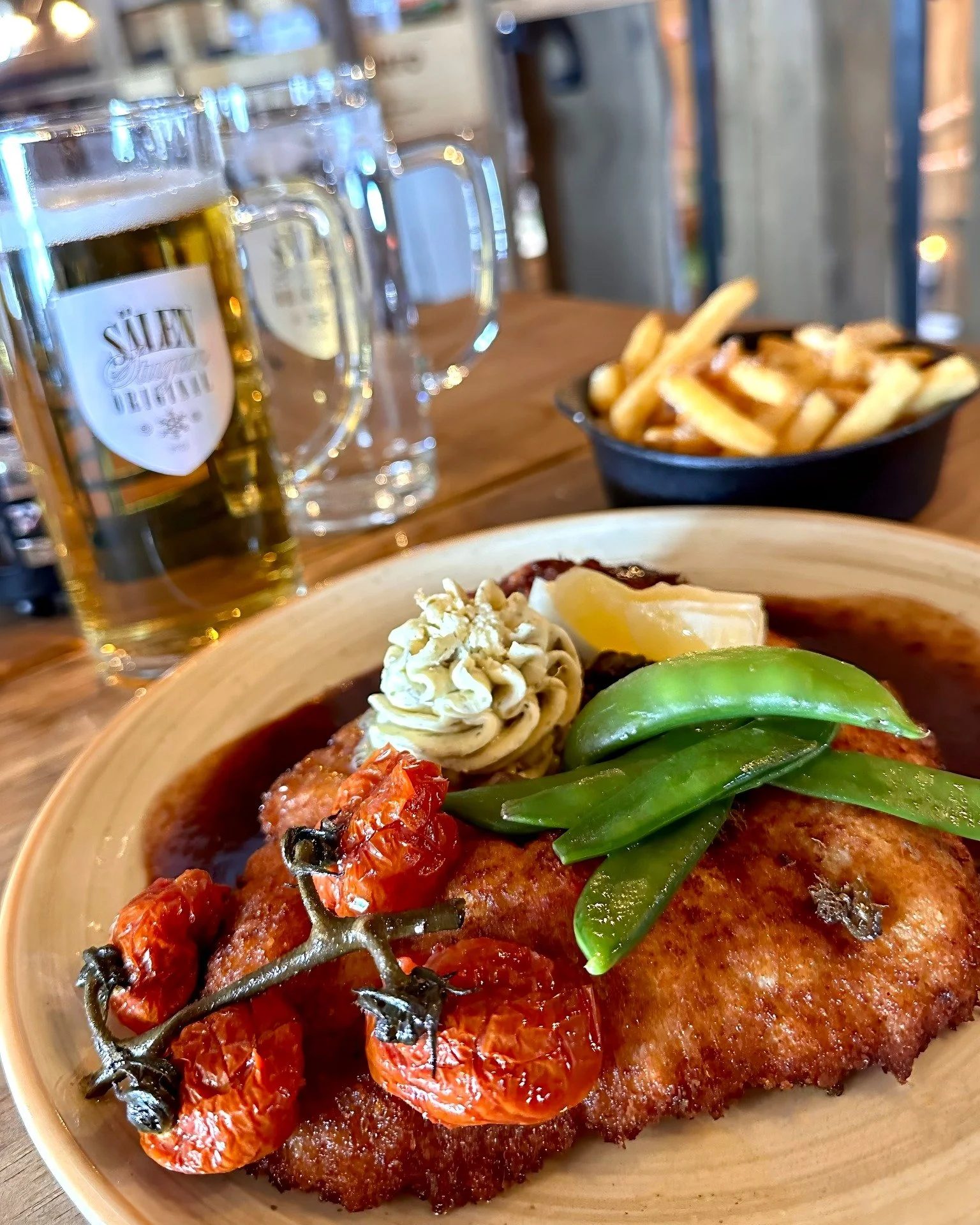 Kan helgen b&ouml;rja b&auml;ttre &auml;n med en Schnitzel Original och en S&auml;lenstugan Lager!?😍 V&aring;r nyfriterade fl&auml;skschnitzel med sm&ouml;rstekta socker&auml;rtor, cocktailtomater, friterad kapris och r&ouml;dvinss&aring;s &auml;r e