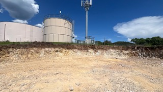 The site cleared for the new raw water tank with the older raw water tank and processed water tank in the background, along with a telecommunications tower