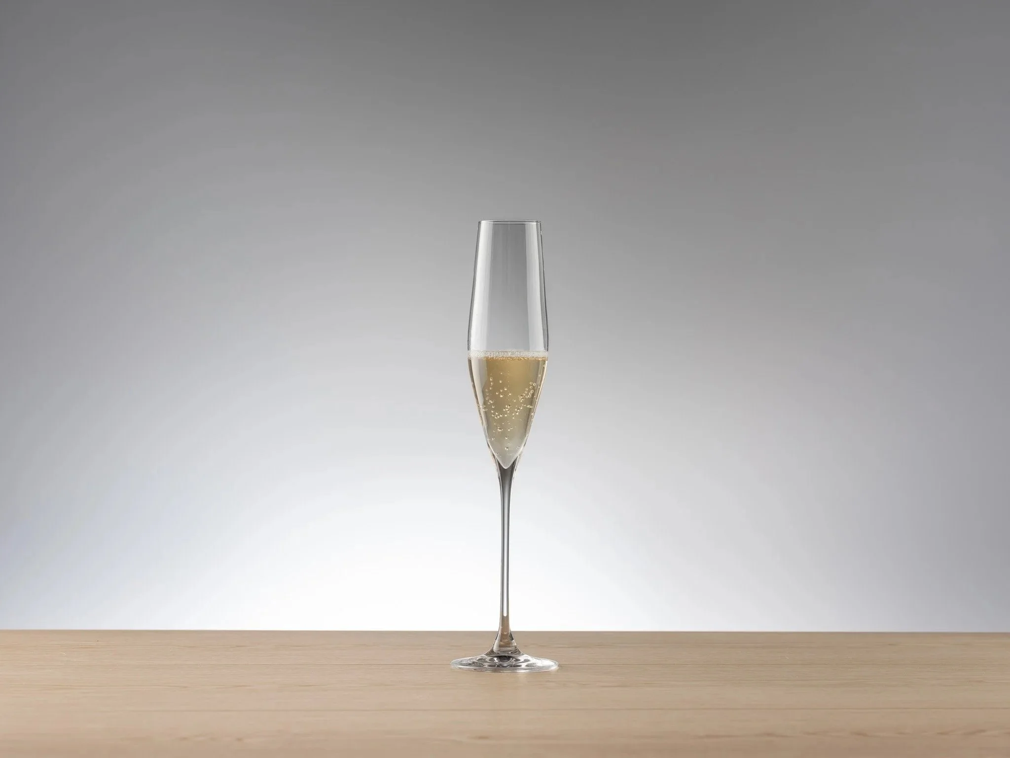 Verona Champagne crystal lead-free glass filled with sparkling wine on a wooden table, against a plain gray background.