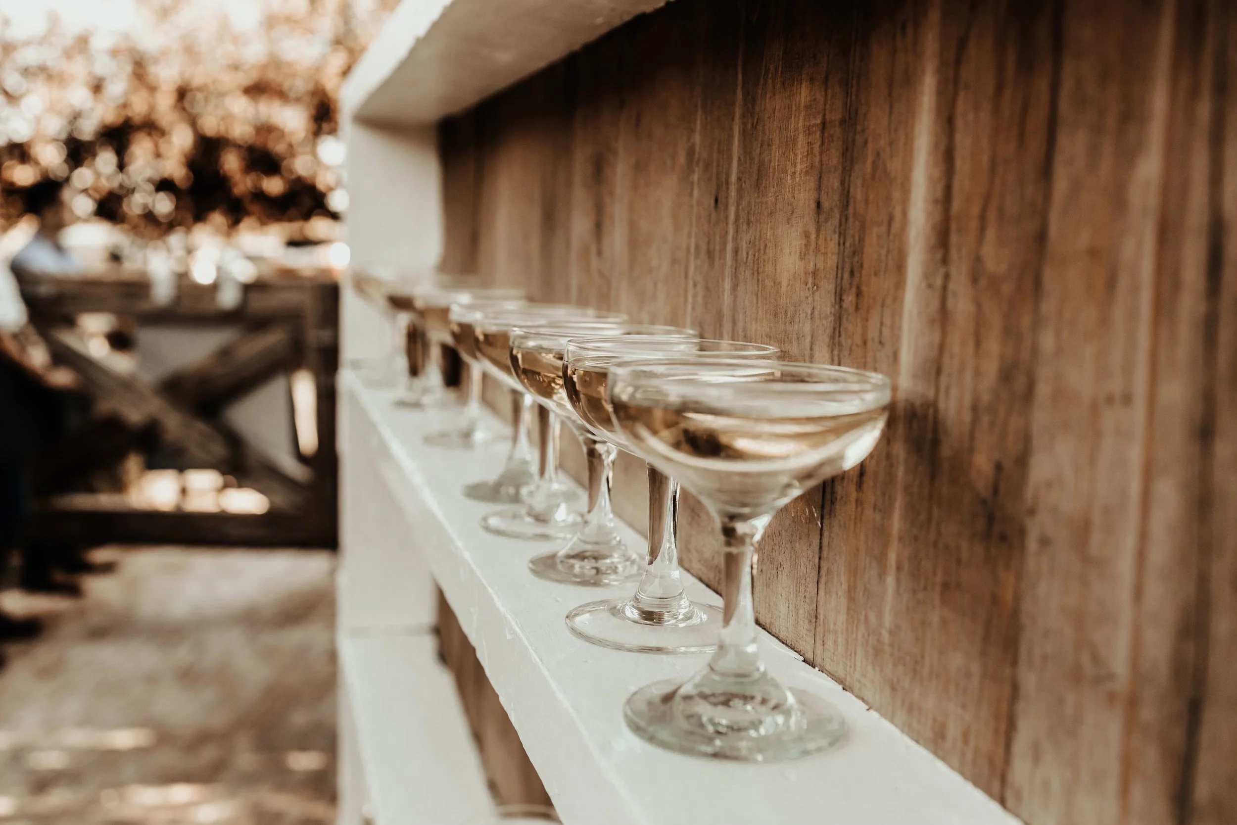 Row of filled champagne glasses on a shelf with blurred background