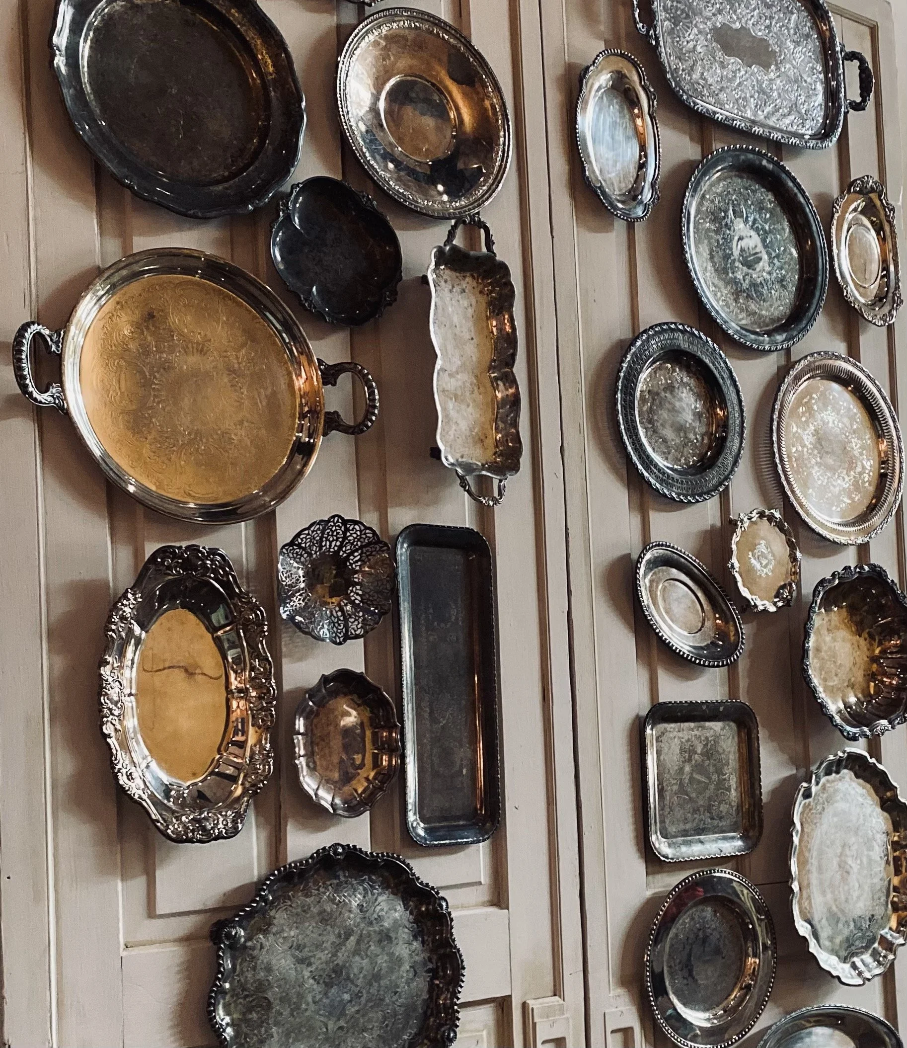Collection of vintage silver trays displayed on wall