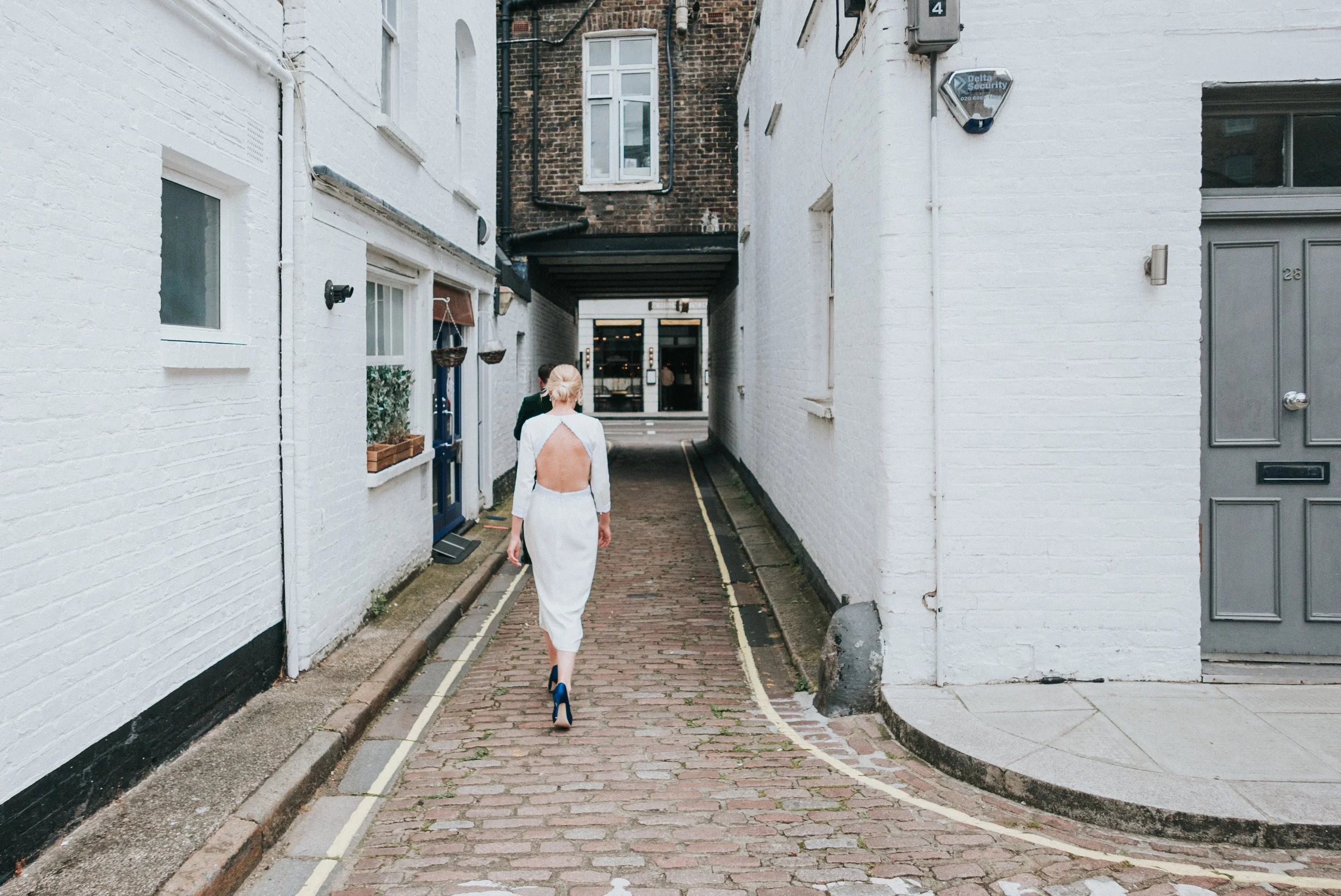 Bride walking down an alleyway with her back to the camera showing a open back dress before a Old Marylebone Town Hall Wedding