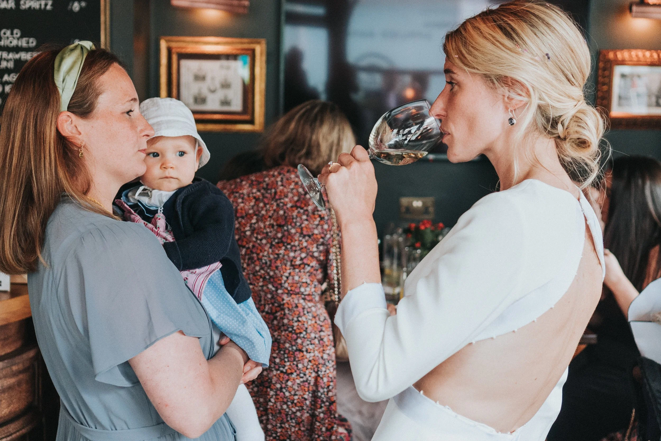 Bride drinking a glass of wine with a Wedding guest at a Old Marylebone Town Hall Wedding