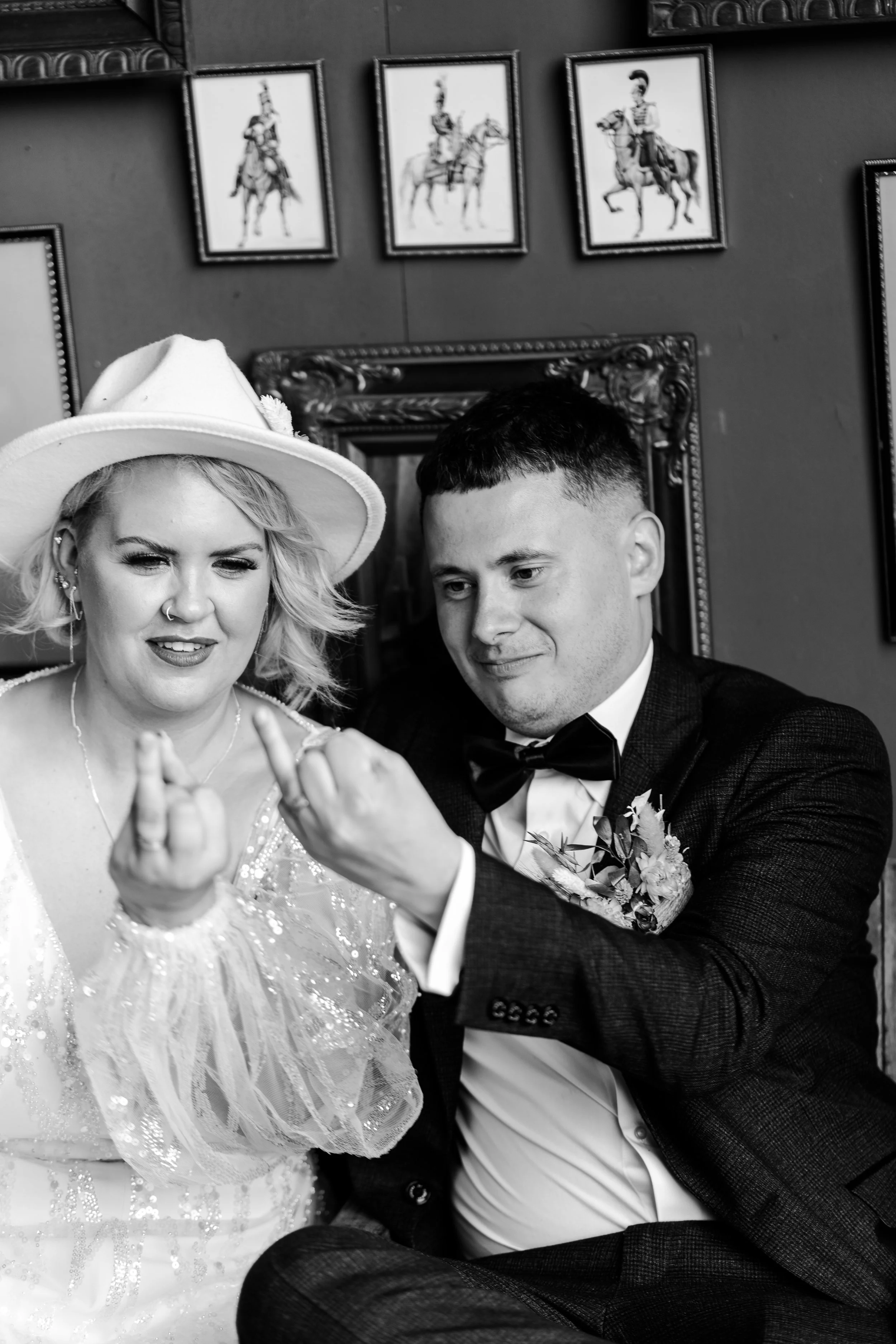Wedding couple sitting together cheekily holding their wedding ring fingers up at a rhyse farm wedding