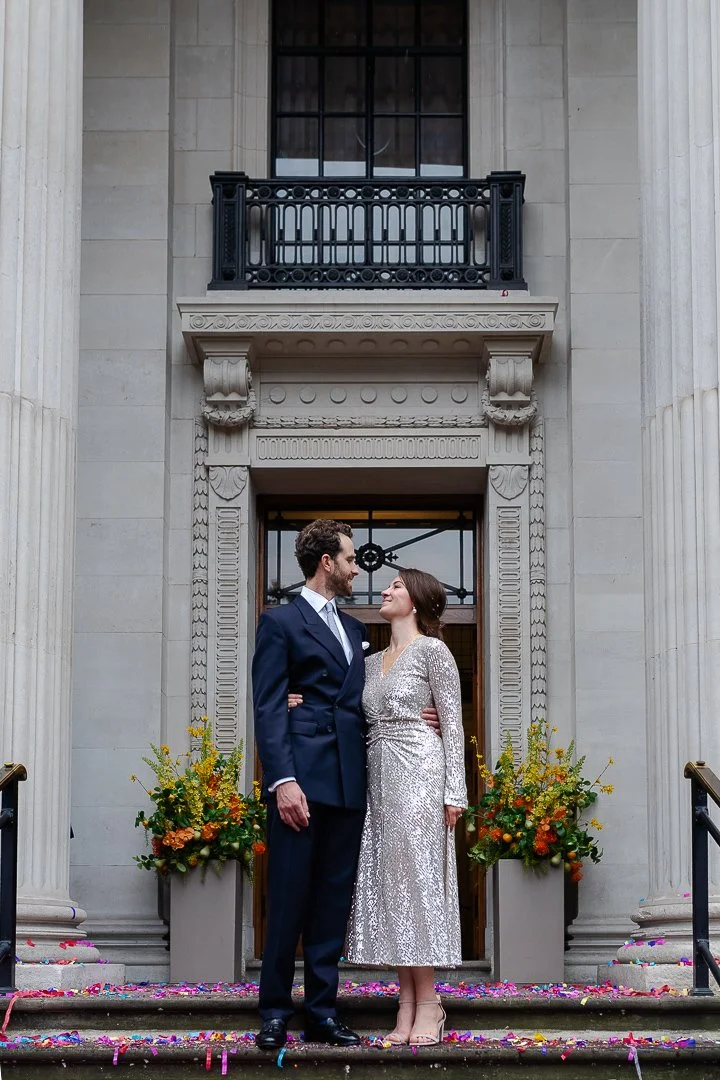 Wedding couple standing on the top step outside looking at each other at the Old Marylebone Town Hall Wedding.