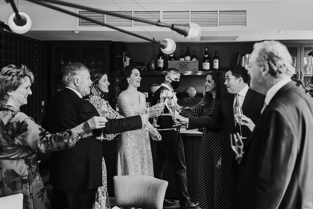 Bride & guests clinking glasses and toasting at a restaurant at the Old Marylebone Town Hall Wedding.